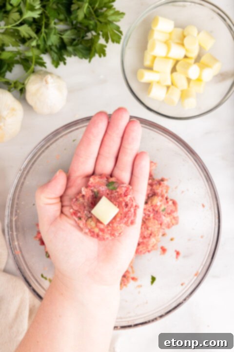 Gooey Mozzarella Meatballs 11 Raw mozzarella stuffed meatball being rolled in hands for a smooth finish.