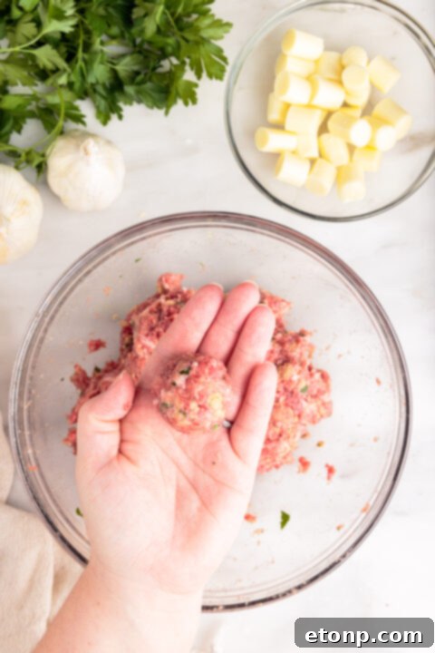 Gooey Mozzarella Meatballs 12 Prepared raw mozzarella stuffed meatballs neatly arranged on a parchment-lined baking sheet.