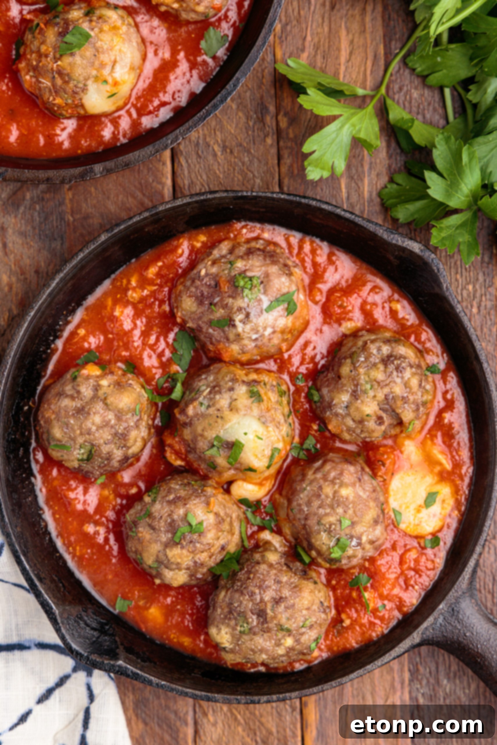 Gooey Mozzarella Meatballs 4 Close-up overhead view of golden-brown Mozzarella Stuffed Meatballs, glistening in a cast iron skillet.