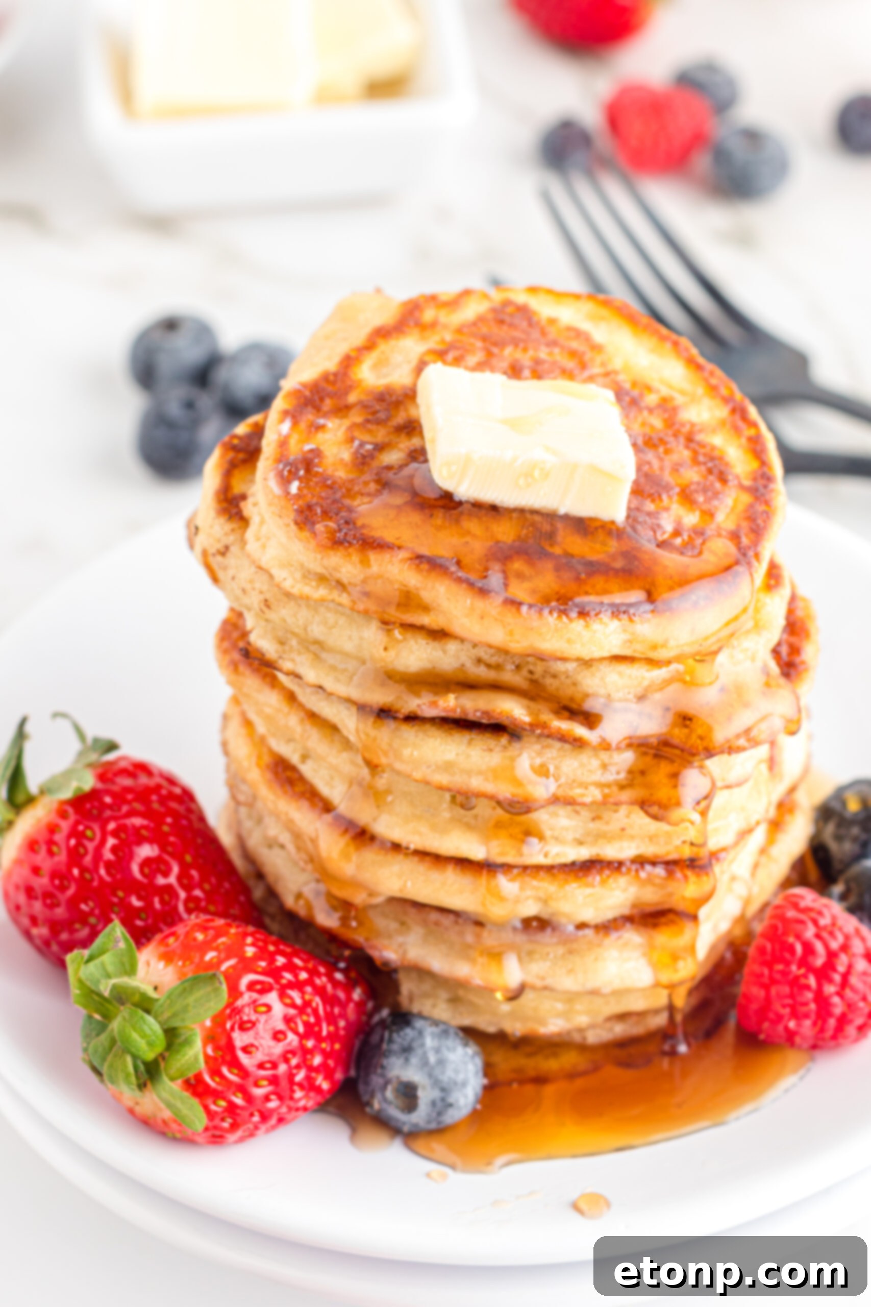 Front view of Mini Pancakes on a white dish served with strawberries and blueberries.