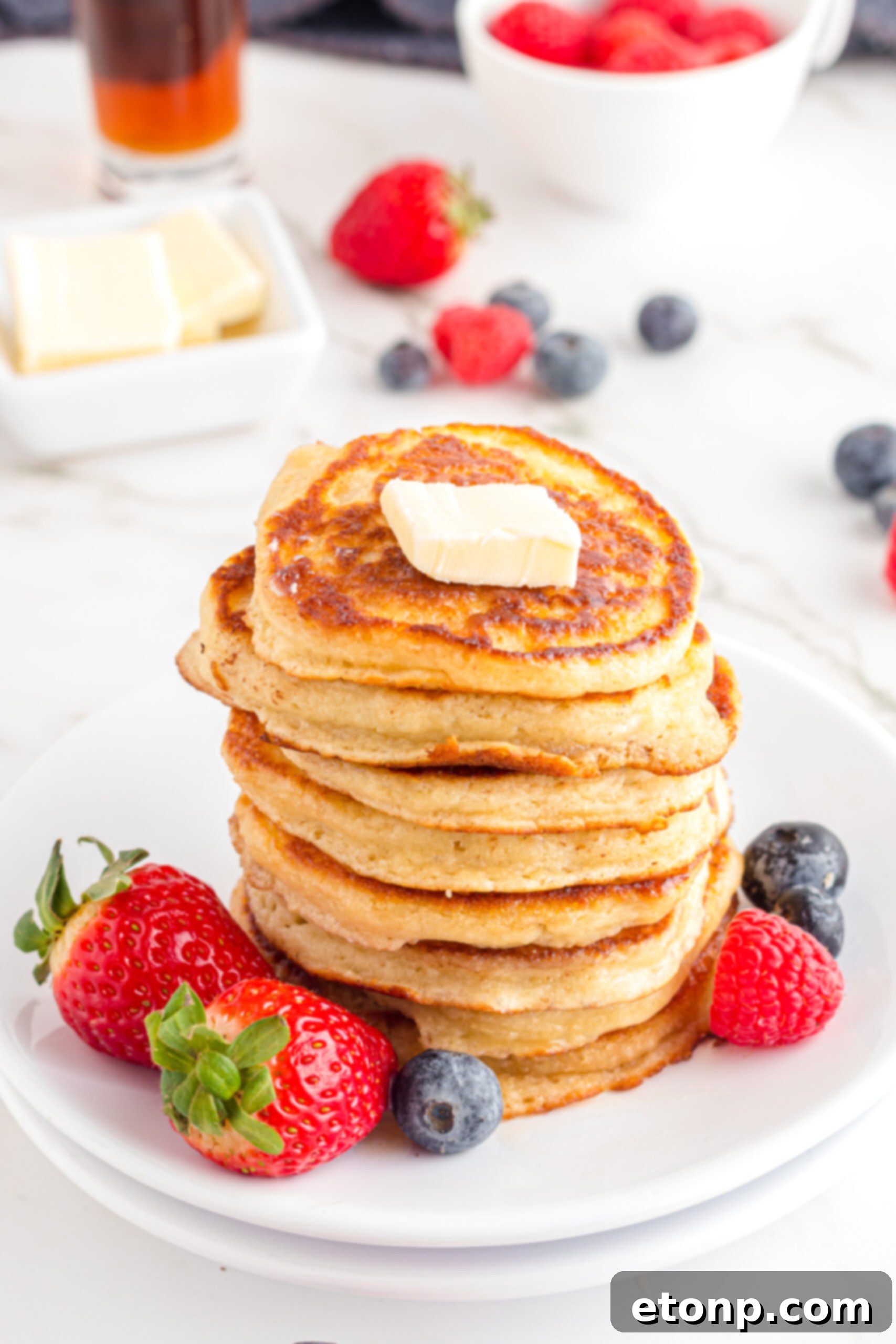 Front view of Mini Pancakes on a white dish served with strawberries and blueberries.