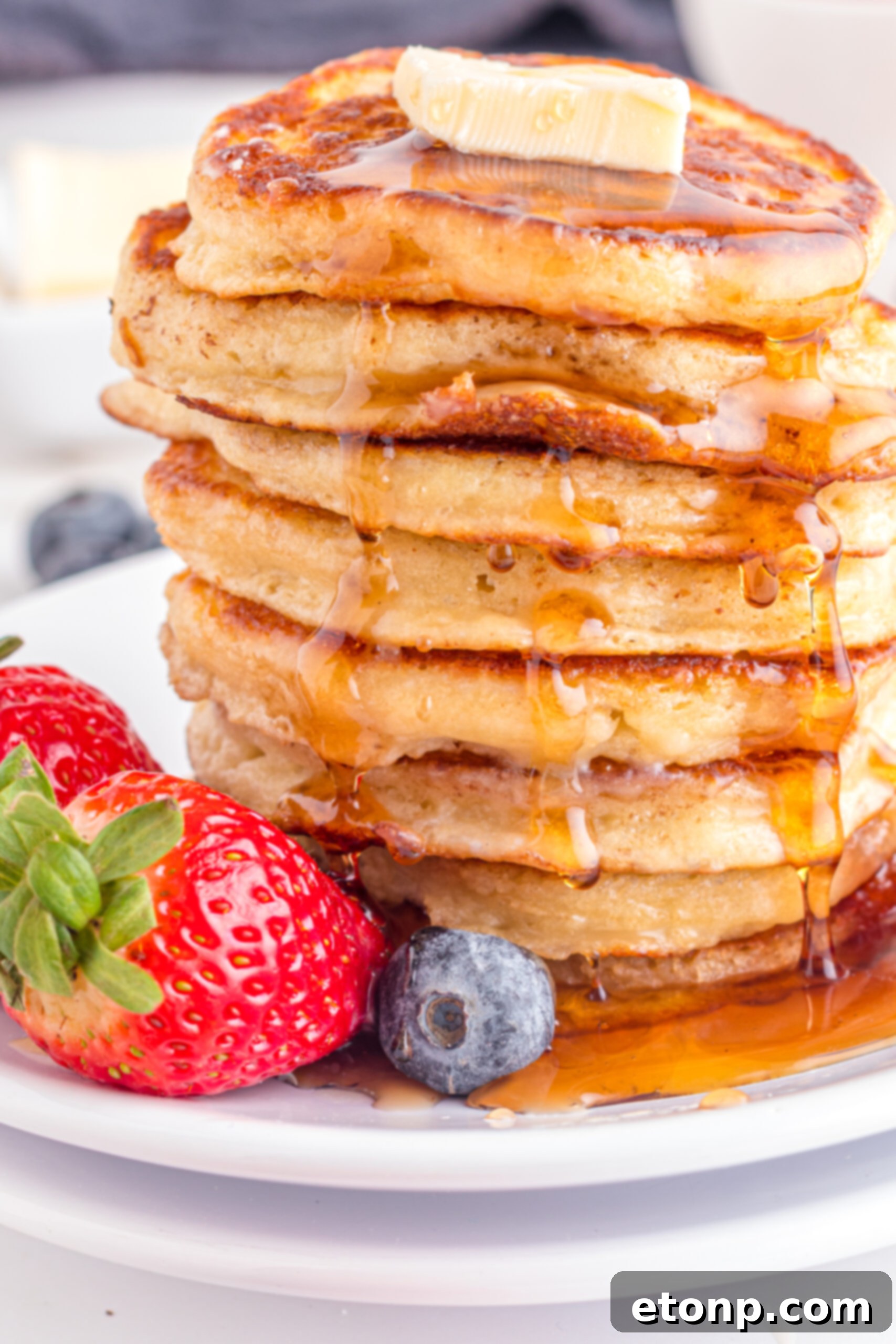 Front view of Mini Pancakes on a white dish served with strawberries and blueberries.