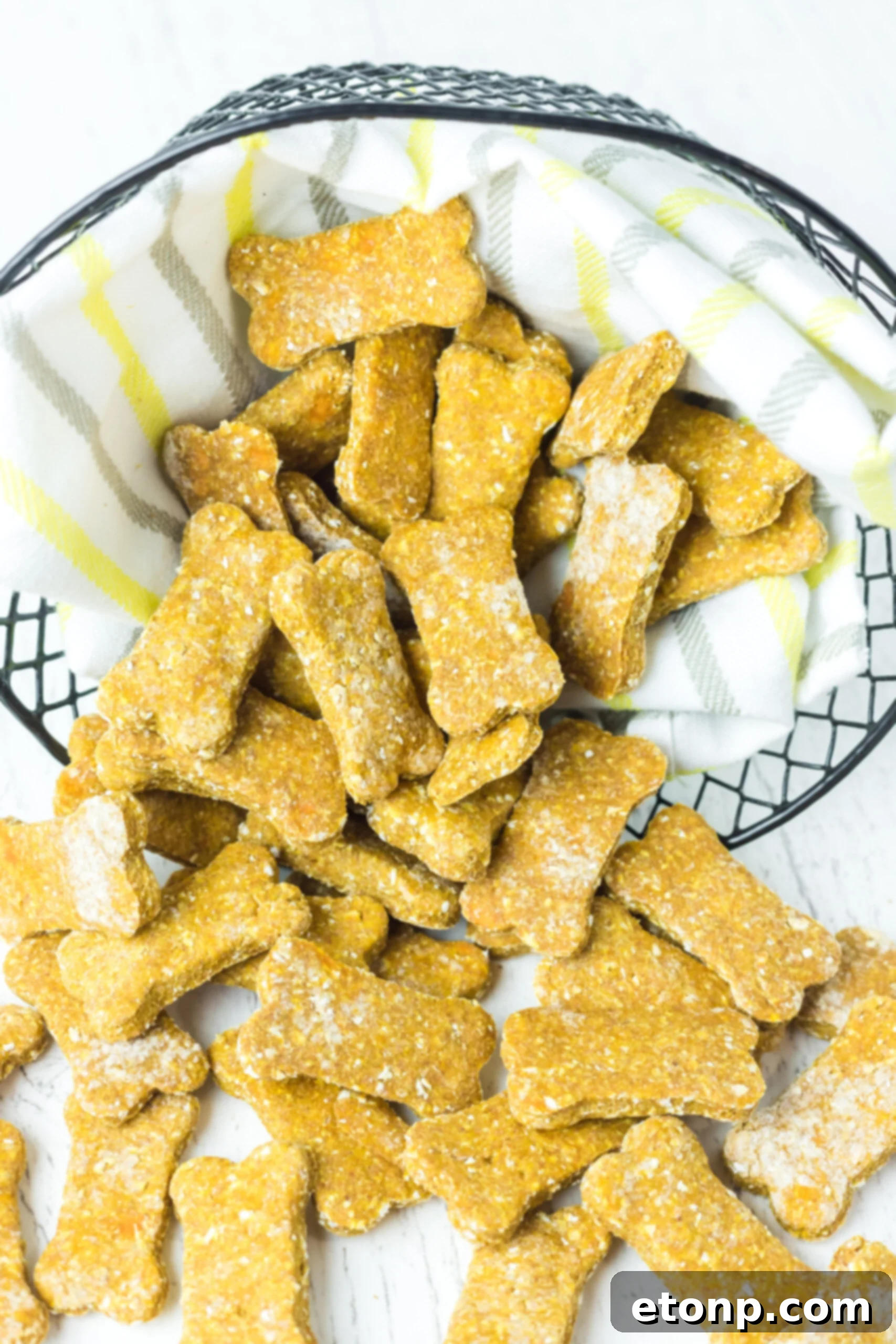 Close up front view of numerous Sweet Potato and Pumpkin Dog Treats overflowing from a rustic wire basket, symbolizing abundance and deliciousness for eager dogs.