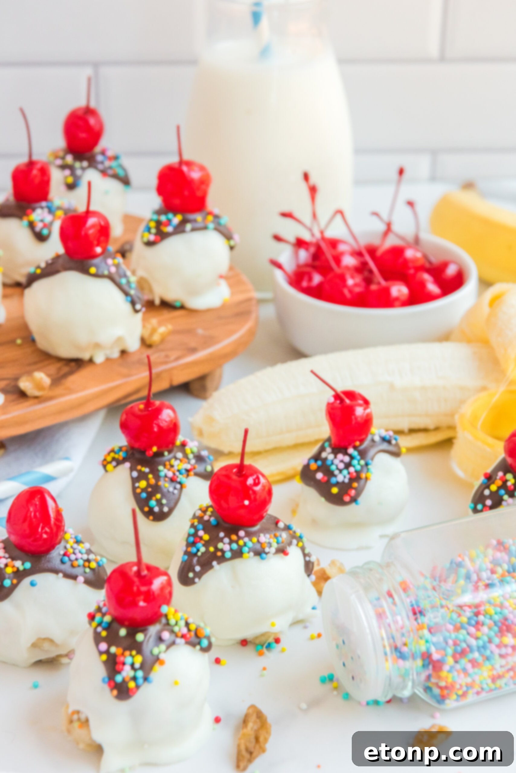 Front view of Banana Truffles surrounded by bananas, a bowl of cherries and nuts.