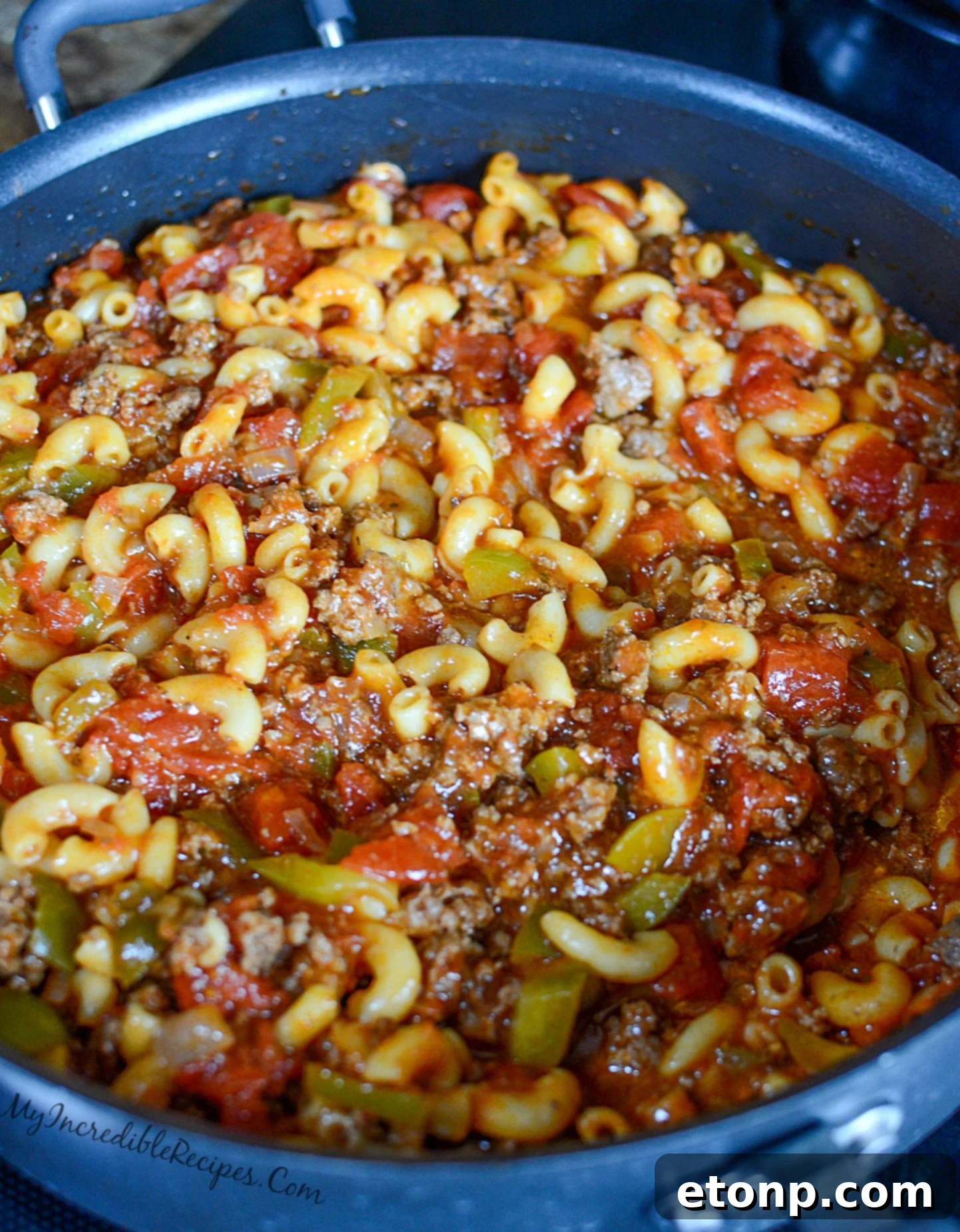 Nana's Classic American Chop Suey 11 Uncooked elbow macaroni being added to the simmering sauce