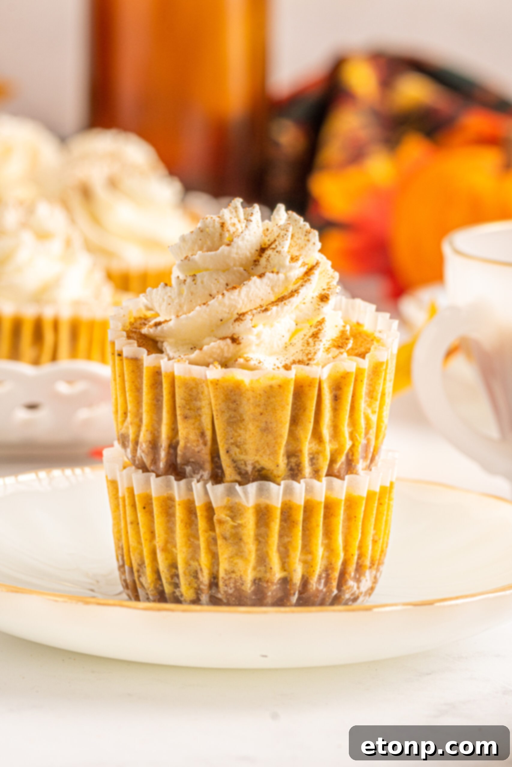 Front view of two Mini Pumpkin Cheesecakes stacked on a white dish, showing off their perfect layers.