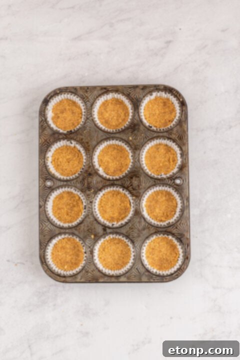 Mini pumpkin cheesecakes cooling on a wire rack after baking.