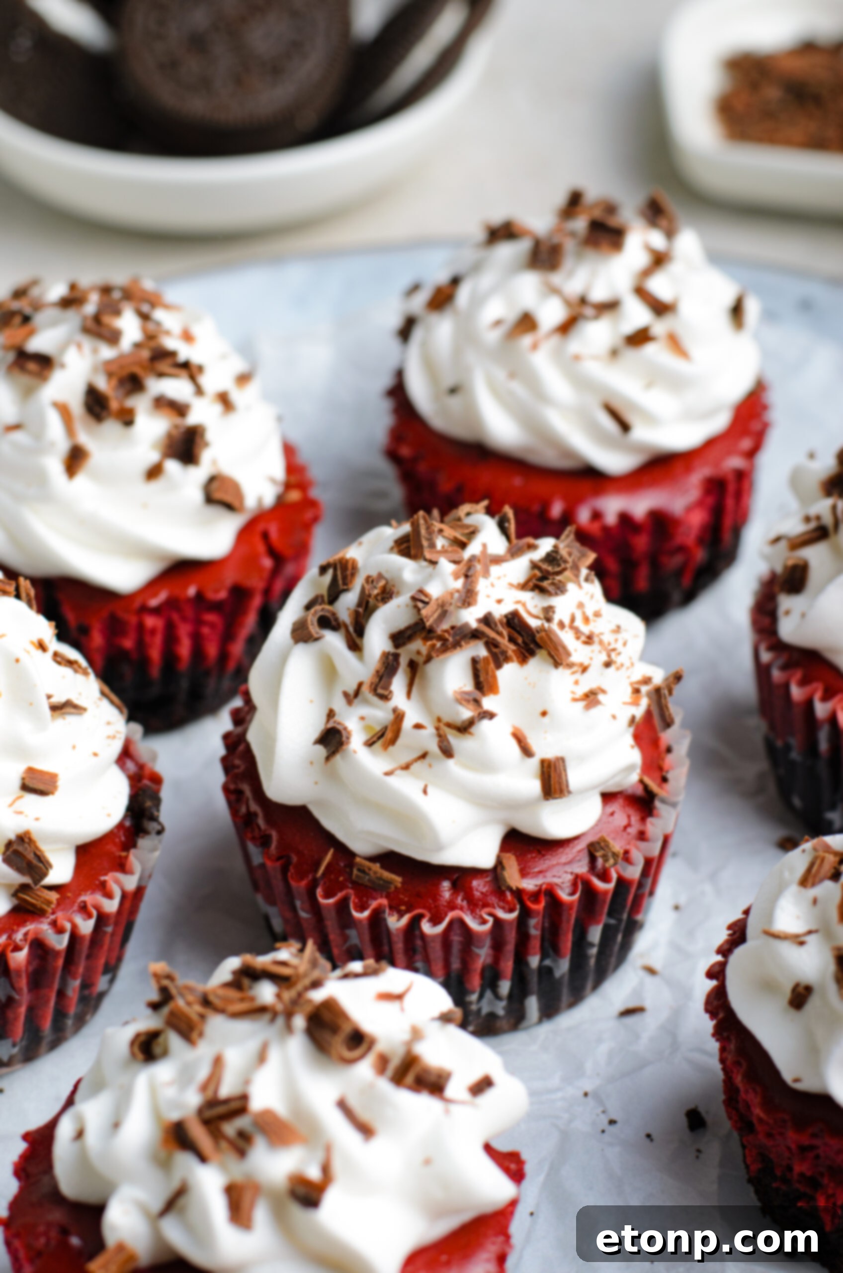 Close up view of Mini Red Velvet Oreo Cheesecakes on a piece of parchment paper.
