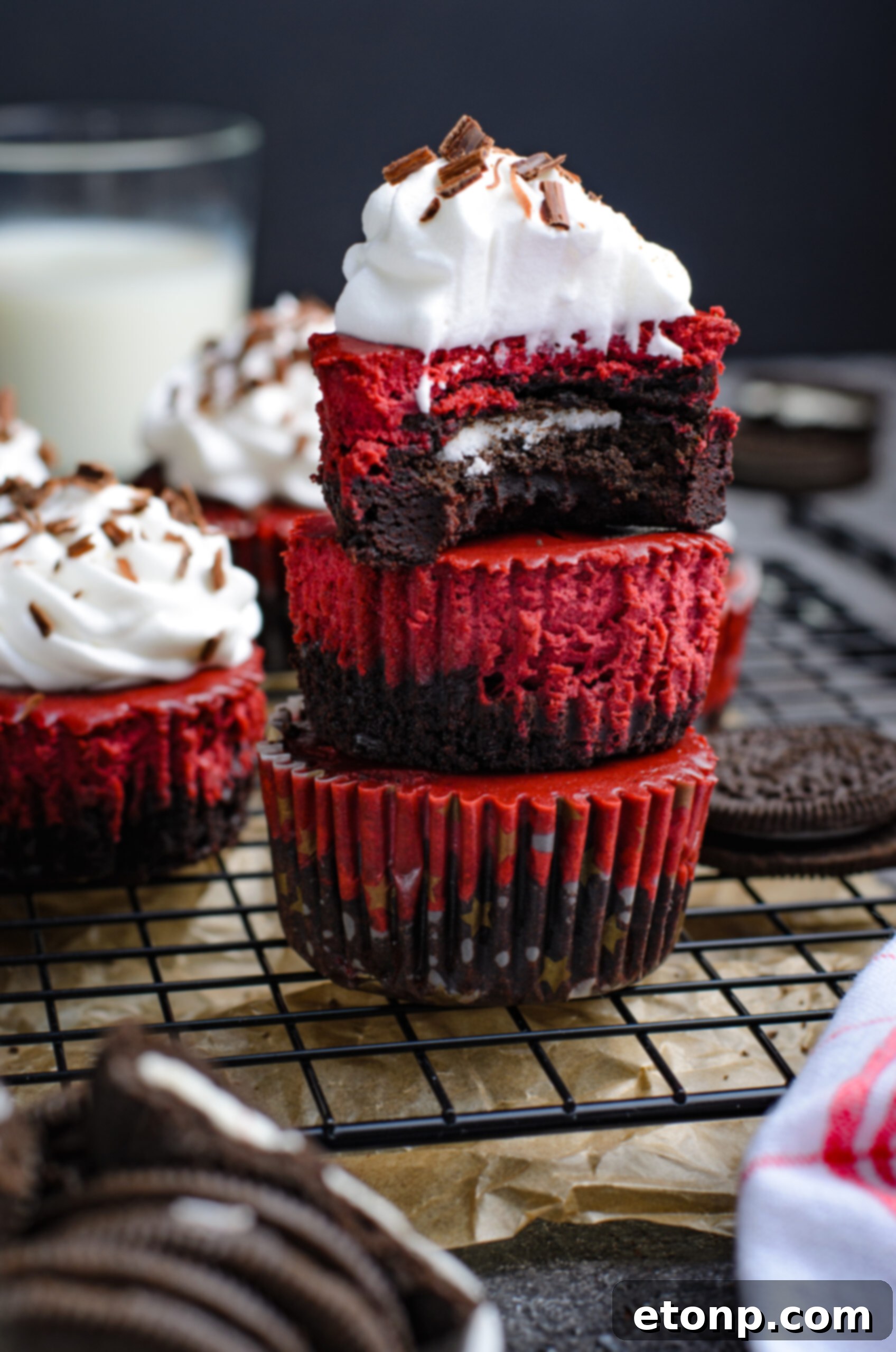 Front view of three Mini Red Velvet Oreo Cheesecakes stacked with a bite removed from the top cheesecake.