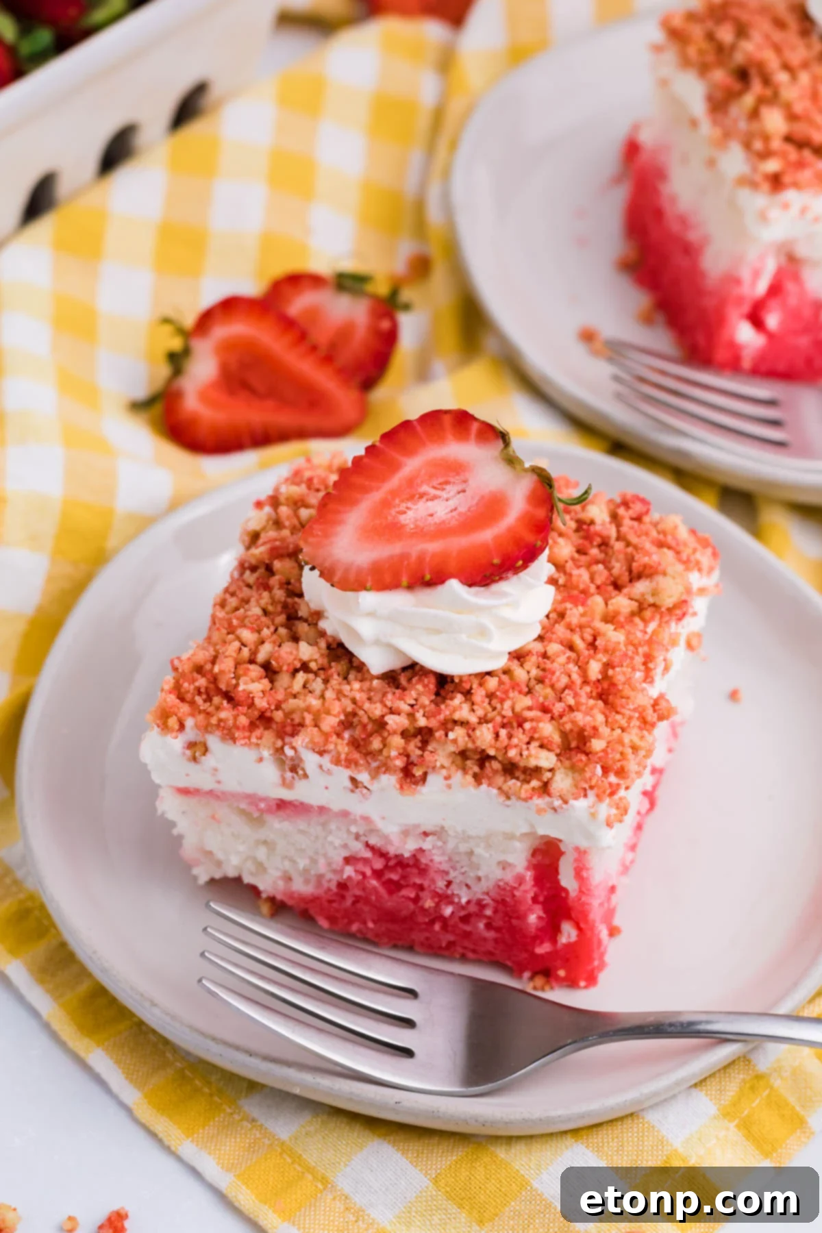 View of a piece of Strawberry Crunch Poke Cake on a white dish, showcasing its layers and crunchy topping.