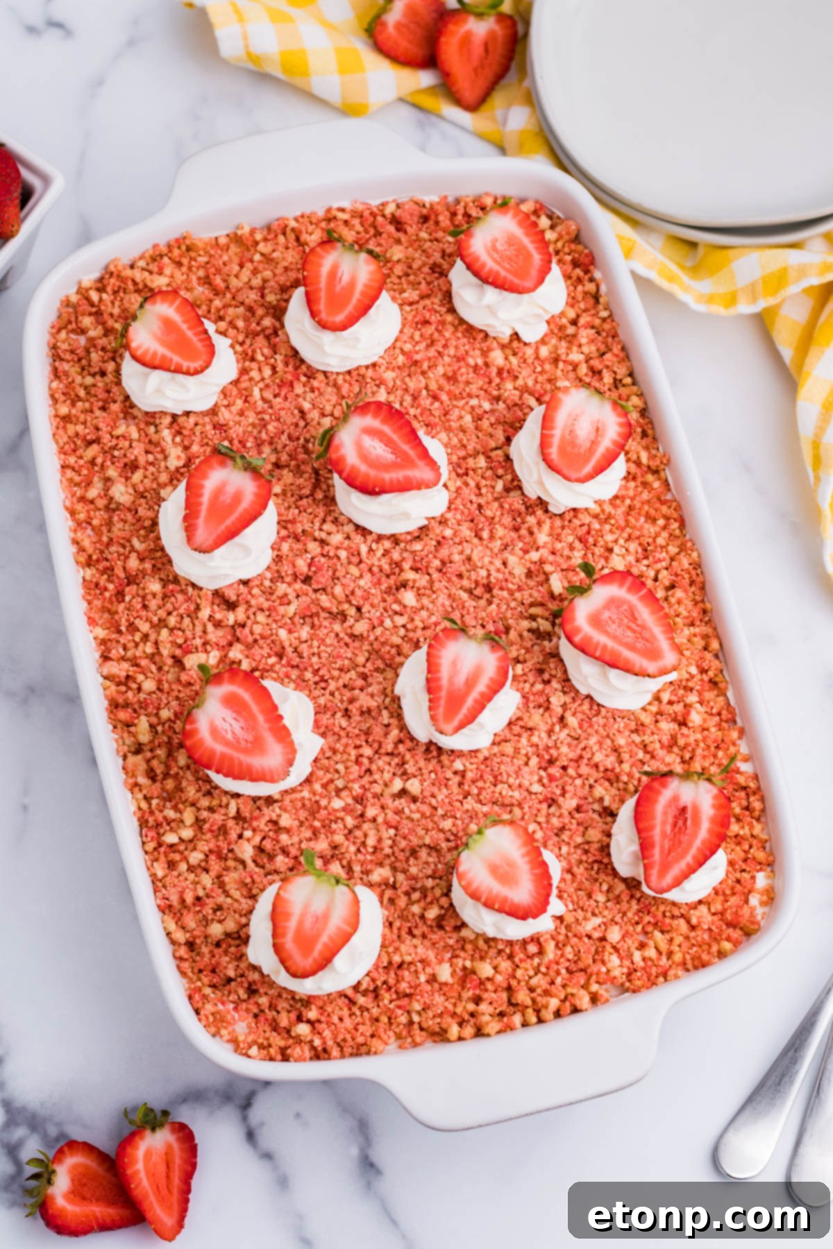 Overhead view of a large Strawberry Crunch Poke Cake in a white baking dish, ready for serving.