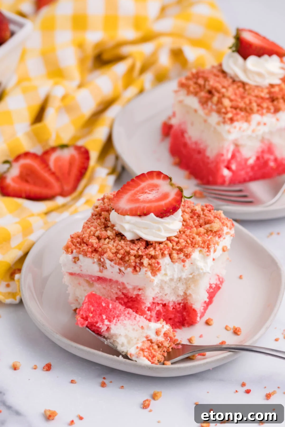 Front view of a piece of Strawberry Crunch Poke Cake with a bite removed by a silver fork, showing the vibrant pink interior.