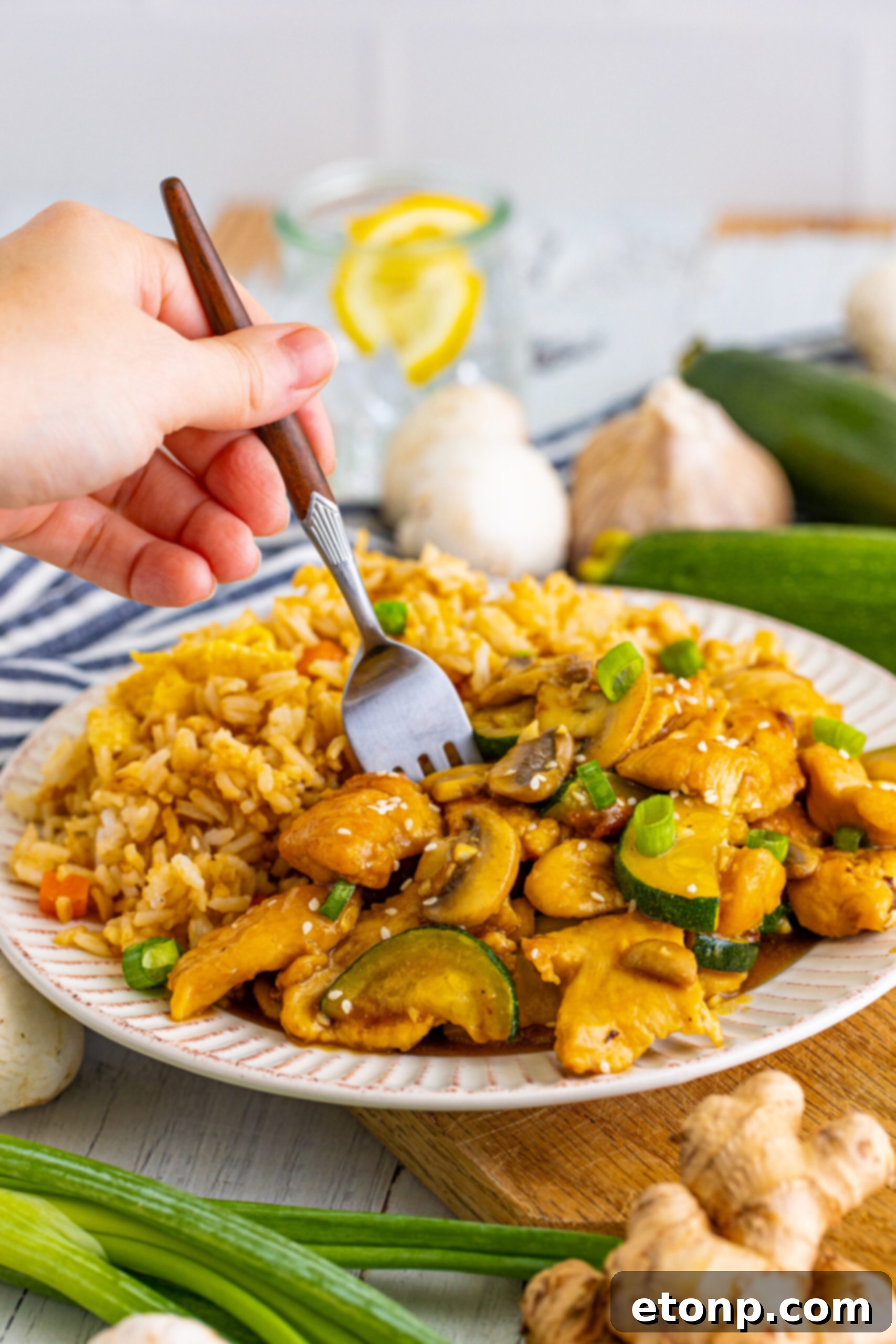 Front view of Panda Express Mushroom Chicken on a white dish served with fried rice with a silver fork.
