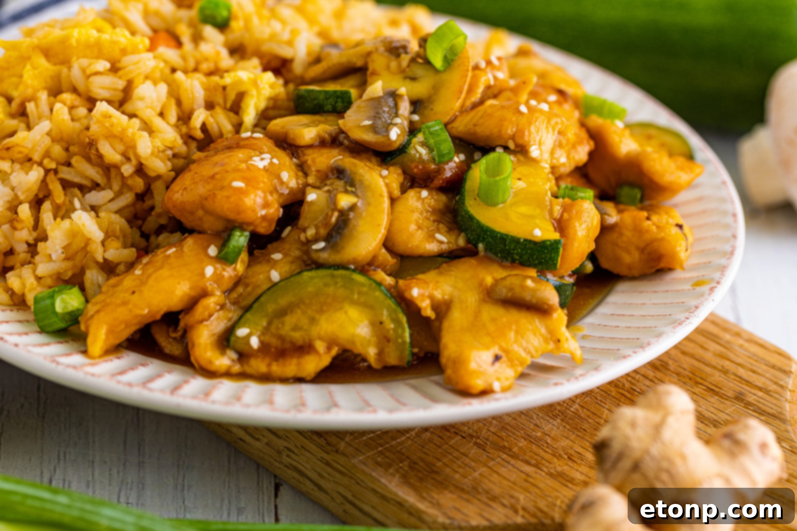 Front view of Panda Express Mushroom Chicken on a white dish served with fried rice.