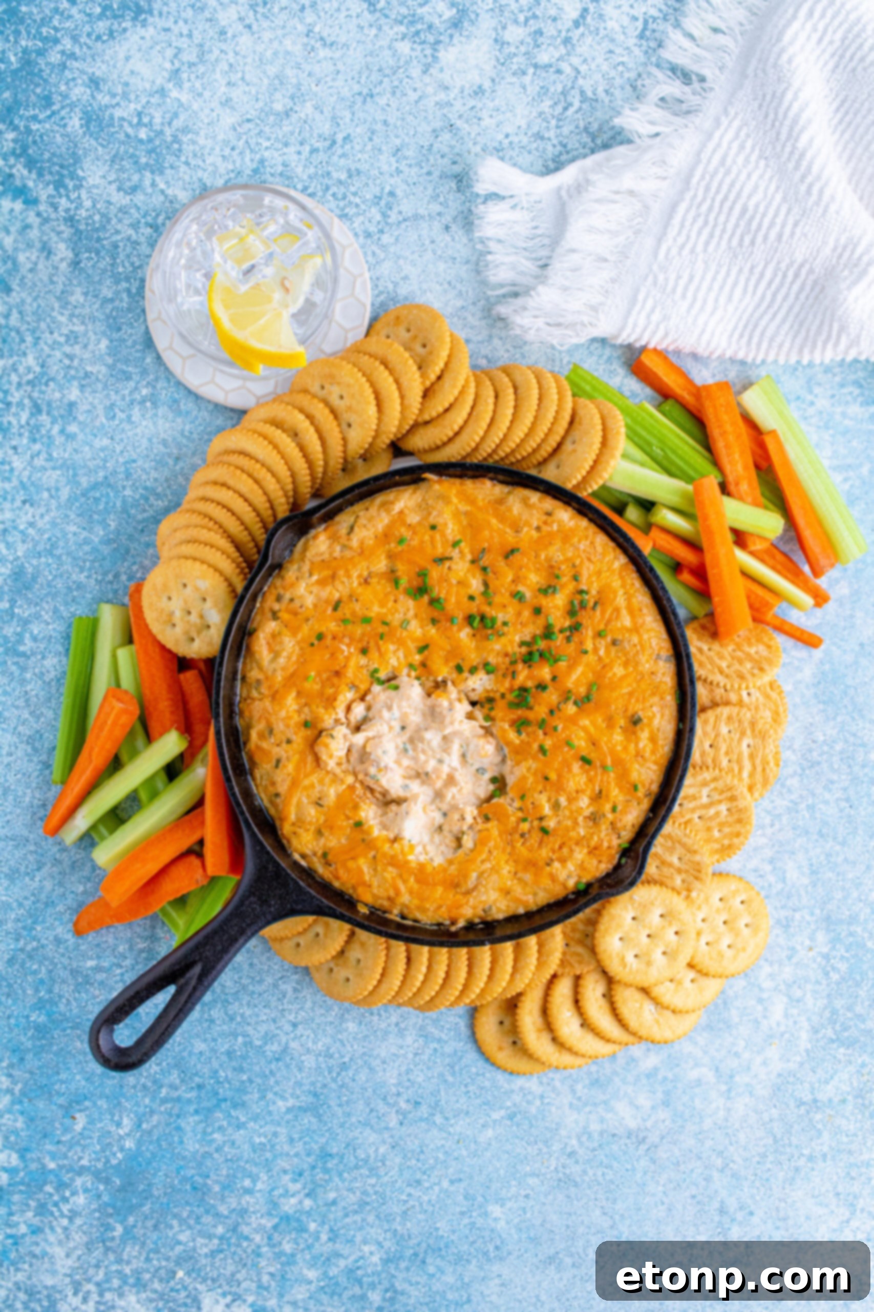 Decadent Crab Delight 17 Overhead view of Crab Dip Recipe in a cast iron skillet served with crackers and vegetables.