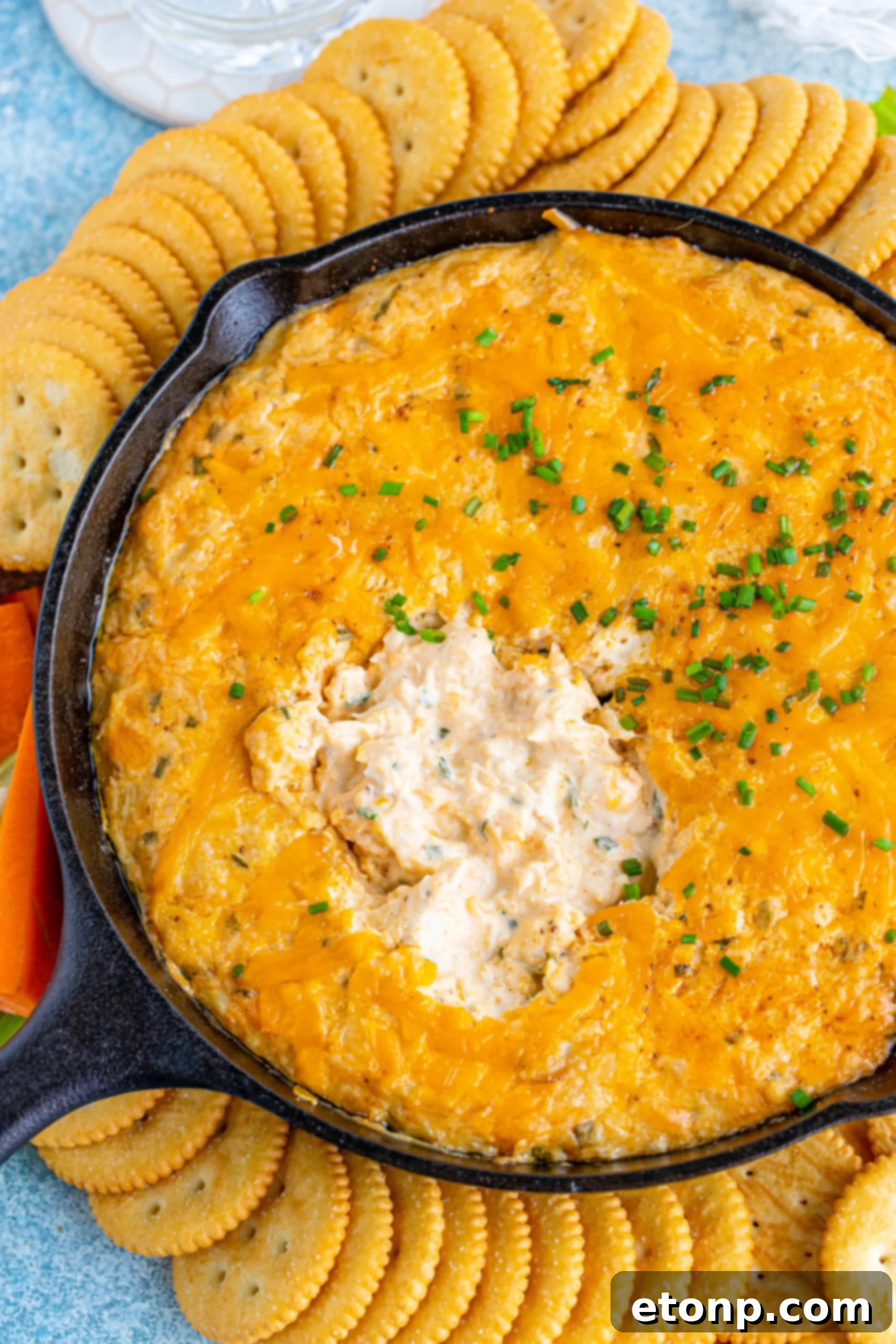 Decadent Crab Delight 3 Overhead view of Crab Dip Recipe in a cast iron skillet served with crackers and vegetables.