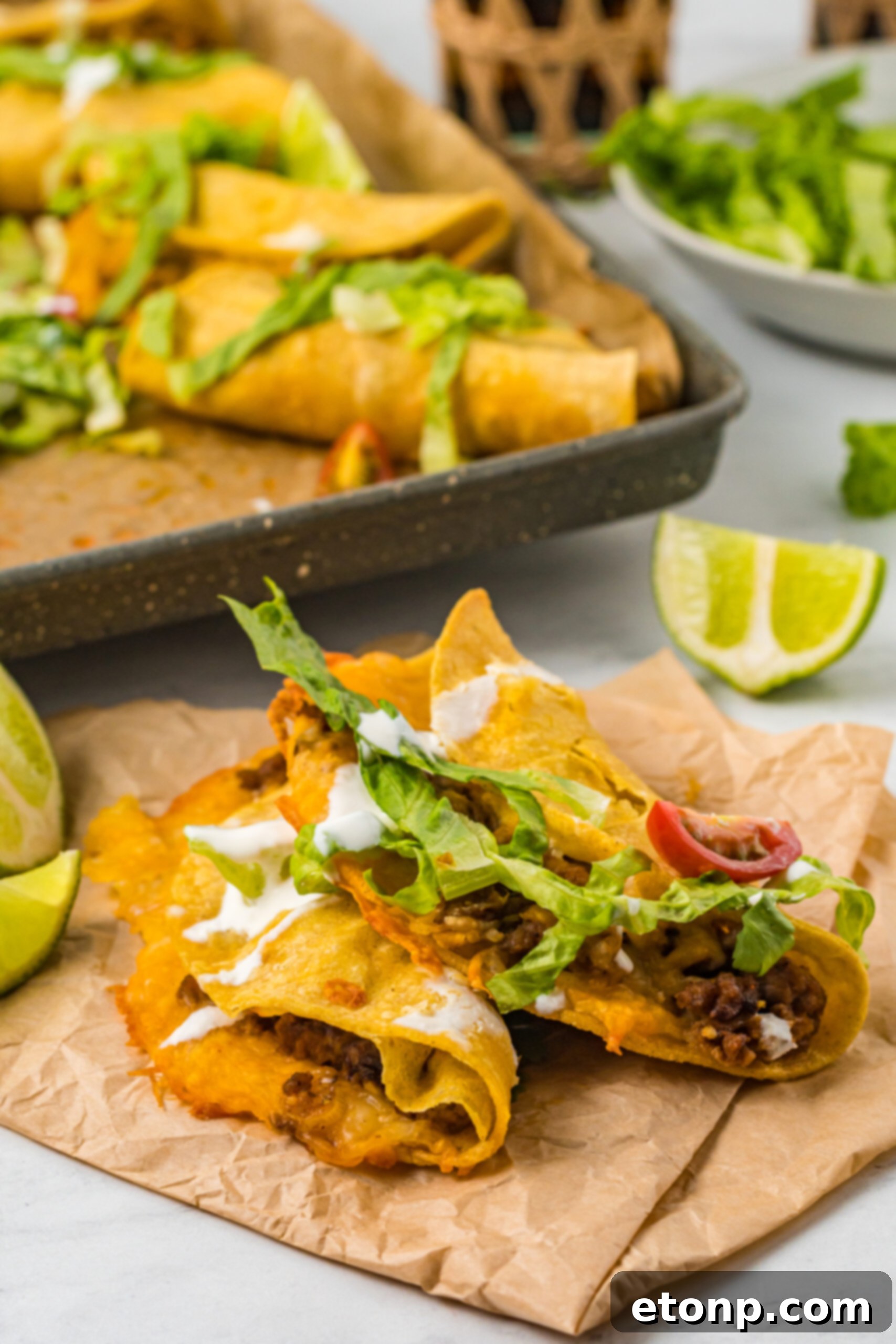 Front view of two Crispy Baked Beef Tacos on parchment paper, ready to be enjoyed.