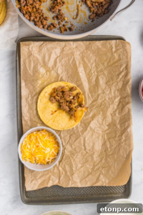 Tacos arranged neatly on a baking sheet, ready for the oven.