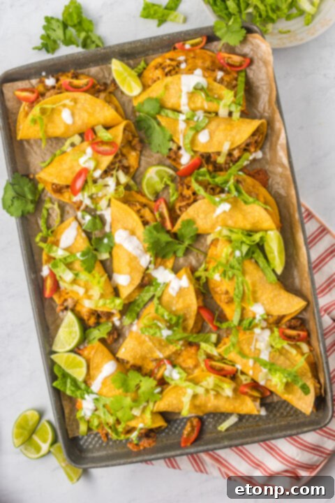 A serving of crispy tacos with various toppings in the background.