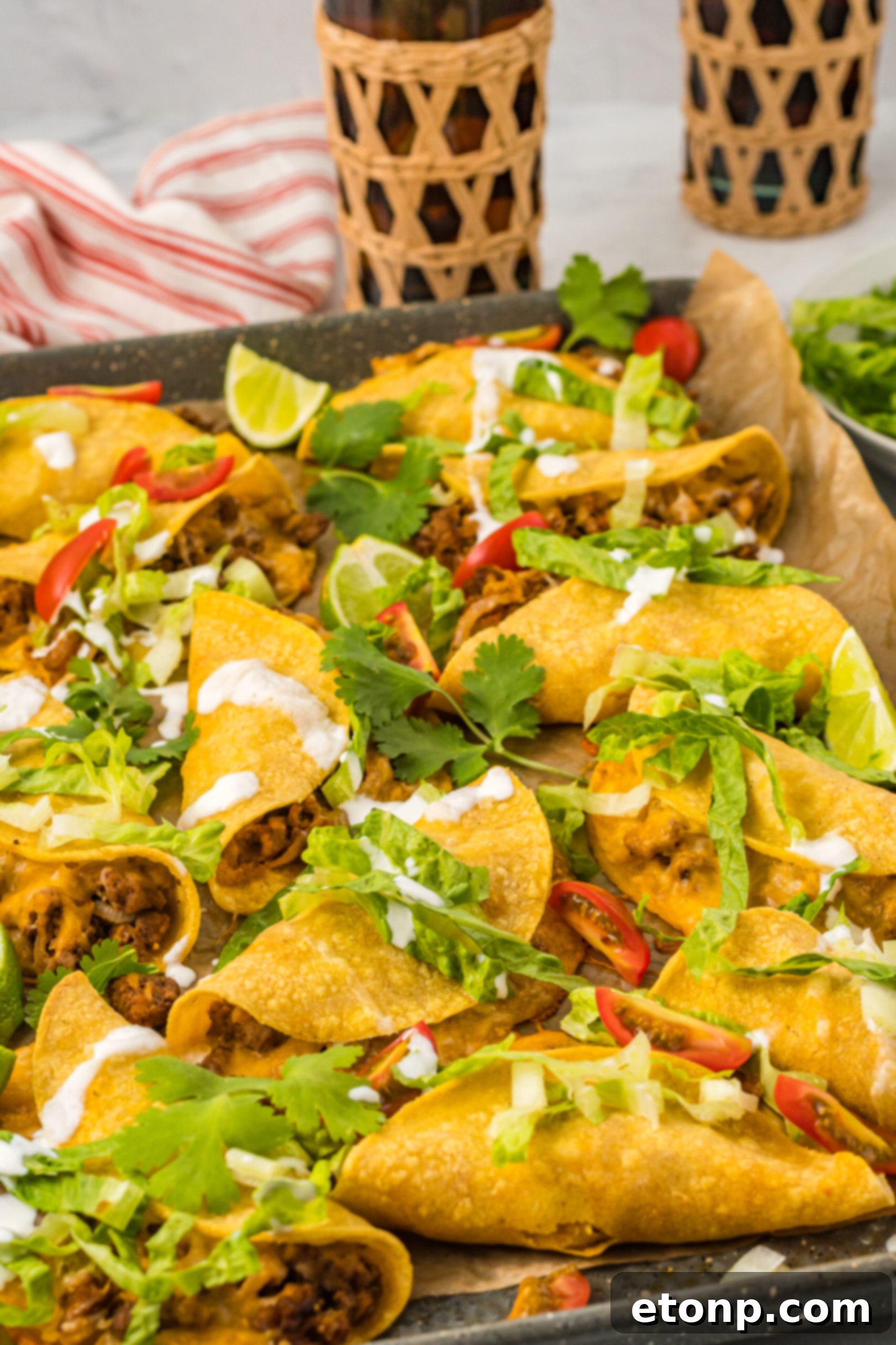 Front view of several Crispy Baked Beef Tacos artfully arranged on a sheet pan, ready to be served.