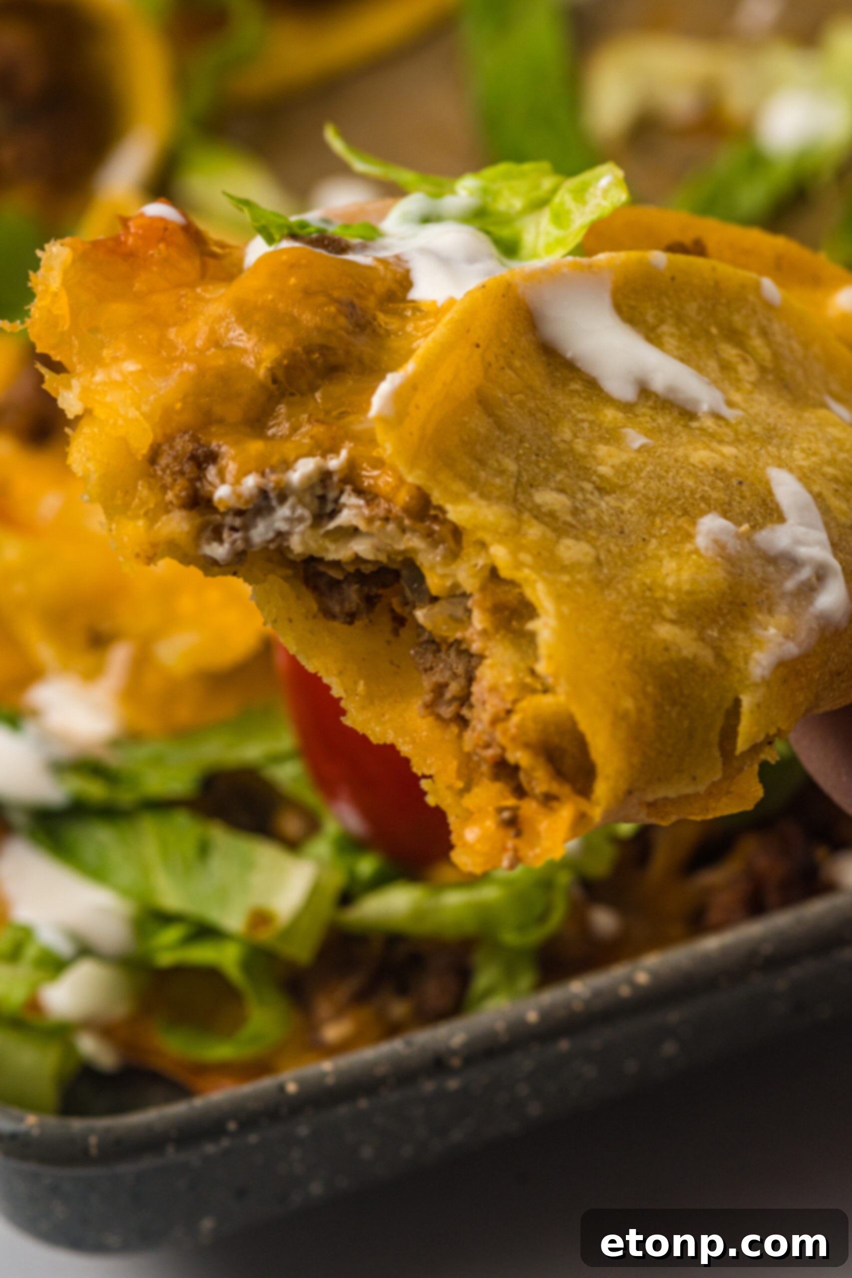 Close-up view of a single Crispy Baked Beef Taco, with a bite taken out to reveal the rich beef filling and melted cheese.