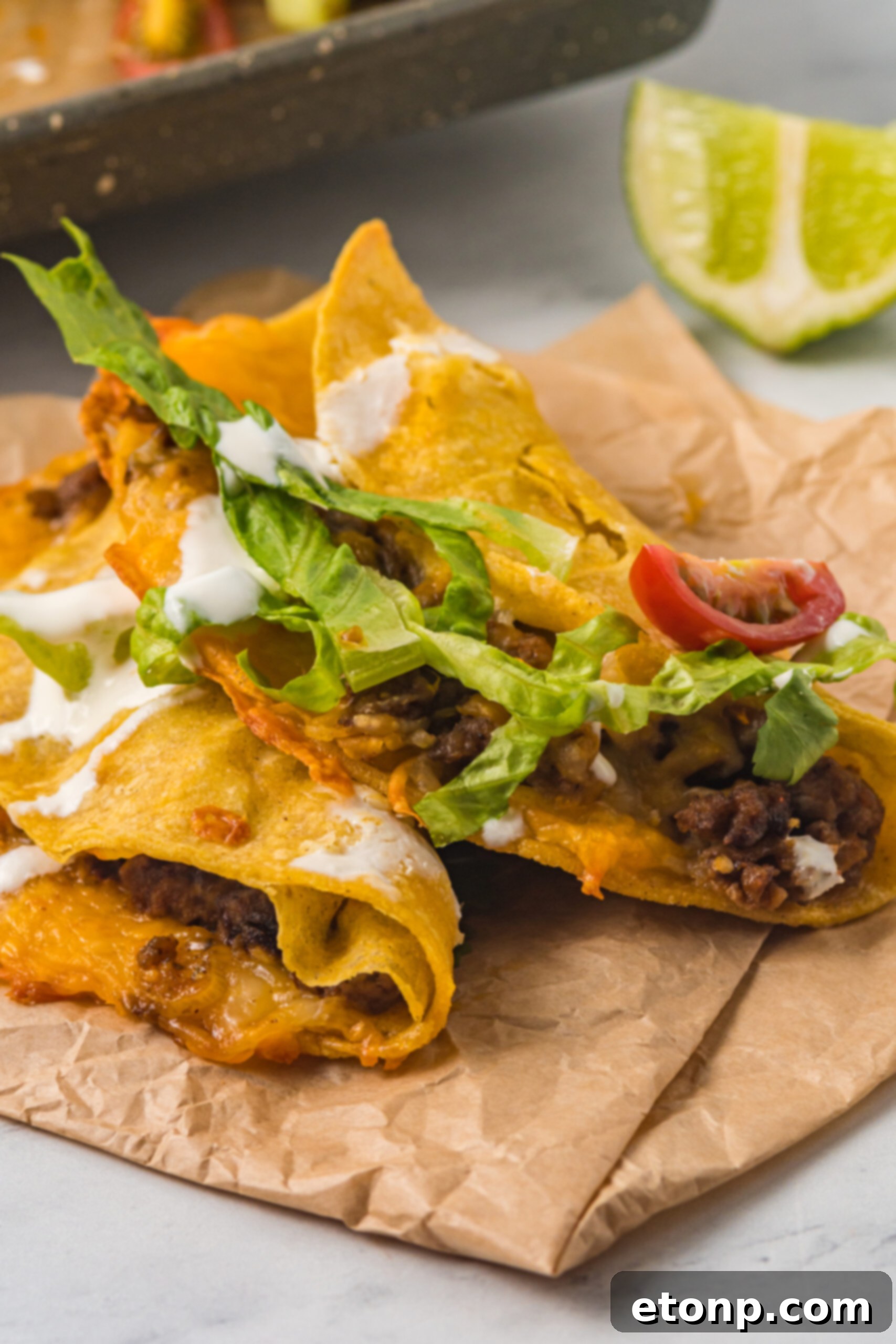 Front view of two Crispy Baked Beef Tacos placed on parchment paper, highlighting their appealing texture.