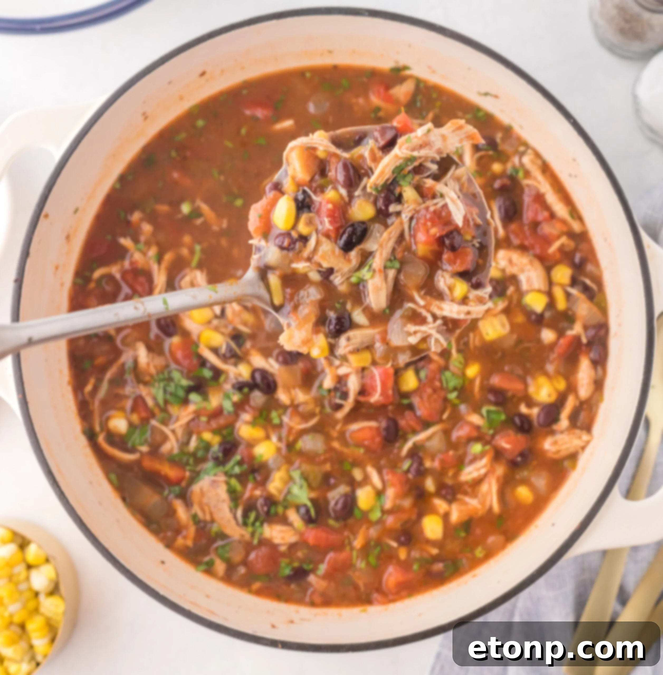 An overhead view of Chicken Taco Soup simmering in a large Dutch oven, filled with colorful ingredients.