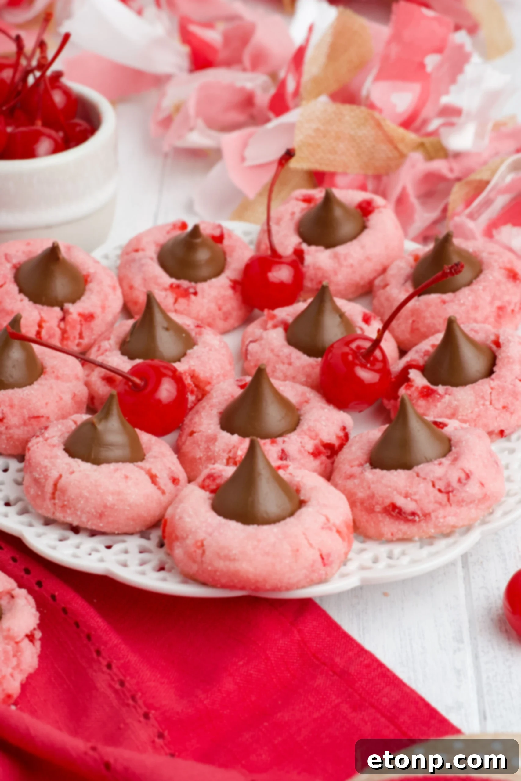 Front view of beautifully arranged Cherry Blossom Cookies on a pristine white dish, showcasing their vibrant pink hue and chocolate kiss center.