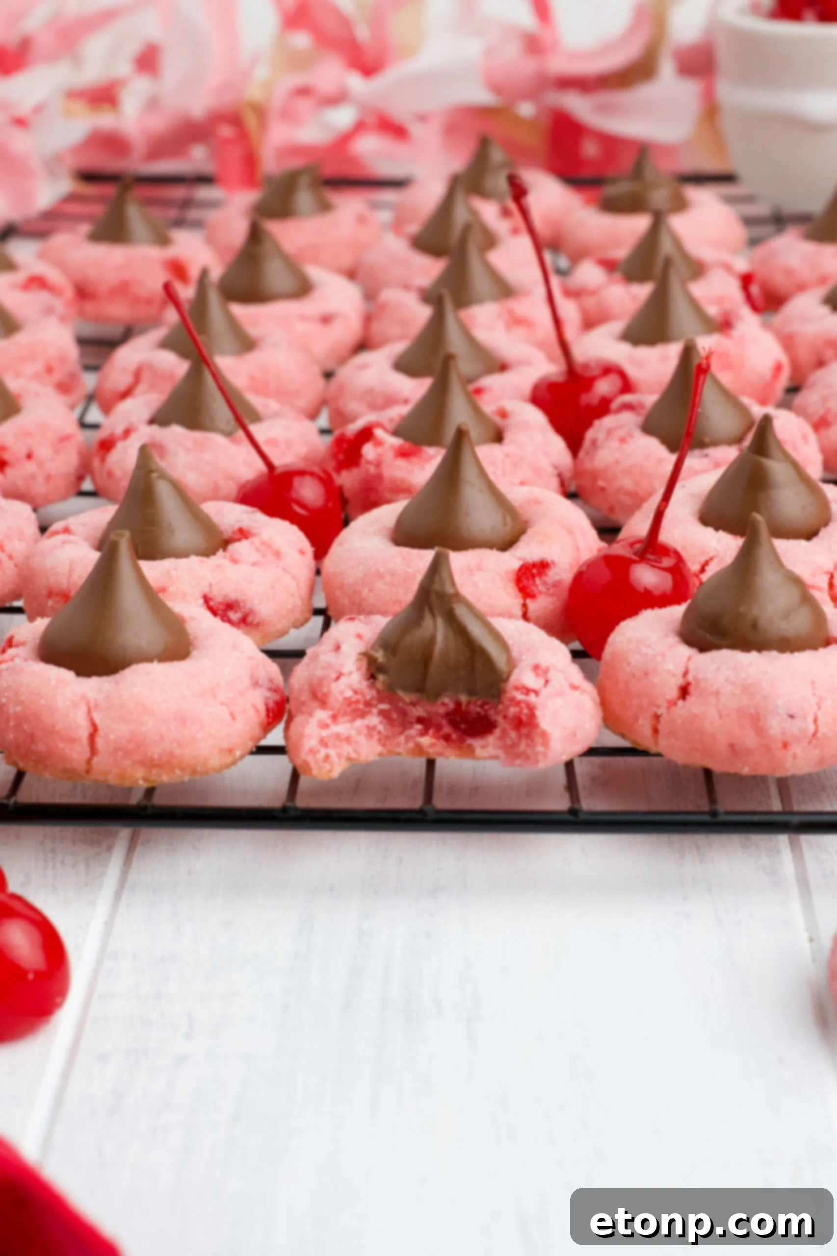 Front view of Cherry Blossom Cookies cooling on a black wire rack, with one cookie showing a bite taken out, revealing its soft interior.