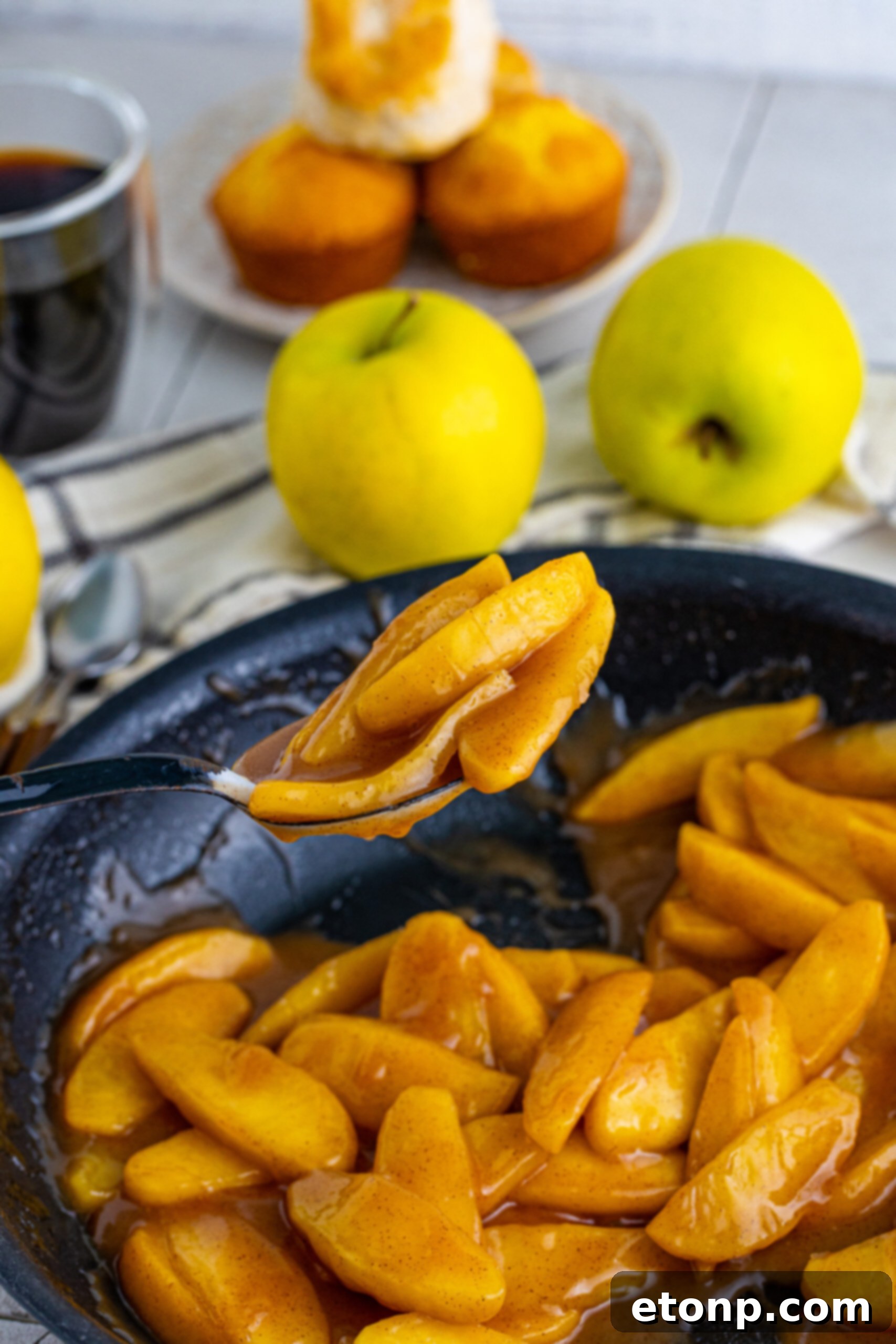 Overhead view of a black spoon holding a perfectly sauced spoonful of Cracker Barrel Fried Apples, ready to be enjoyed.
