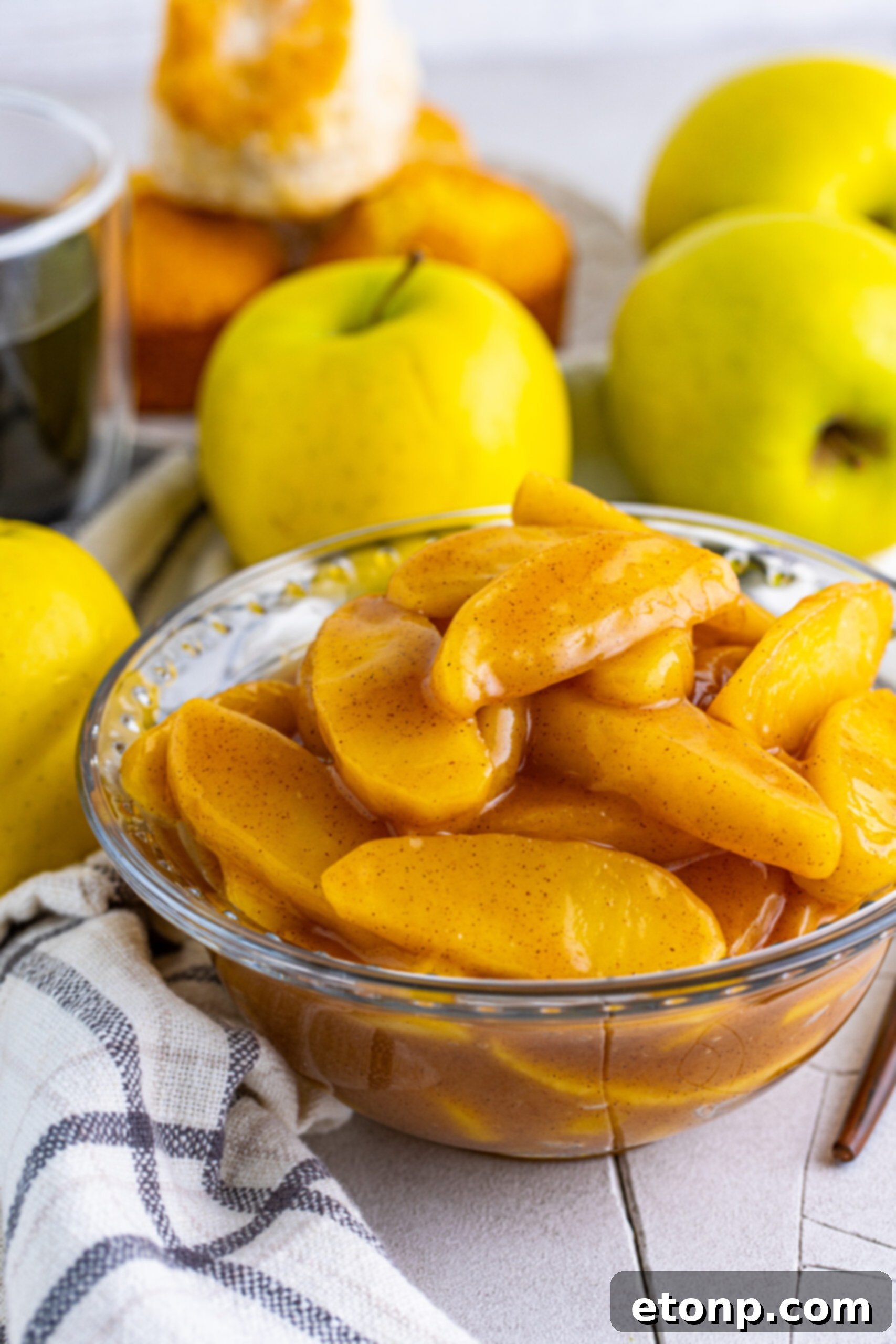 Close up view of the rich, sweet sauce coating each slice of Cracker Barrel Fried Apples in a clear bowl.