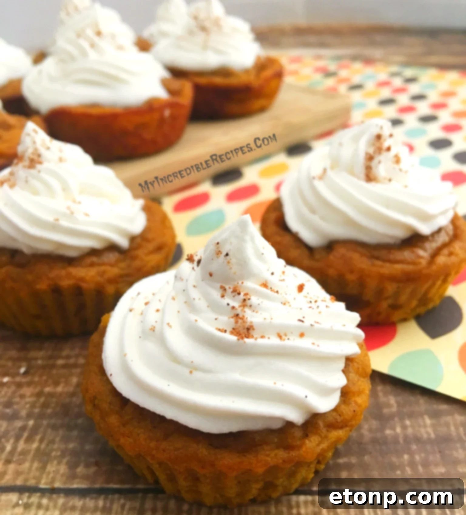 A close-up of a pumpkin pie cupcake with a perfect swirl of whipped cream and a sprinkle of cinnamon.