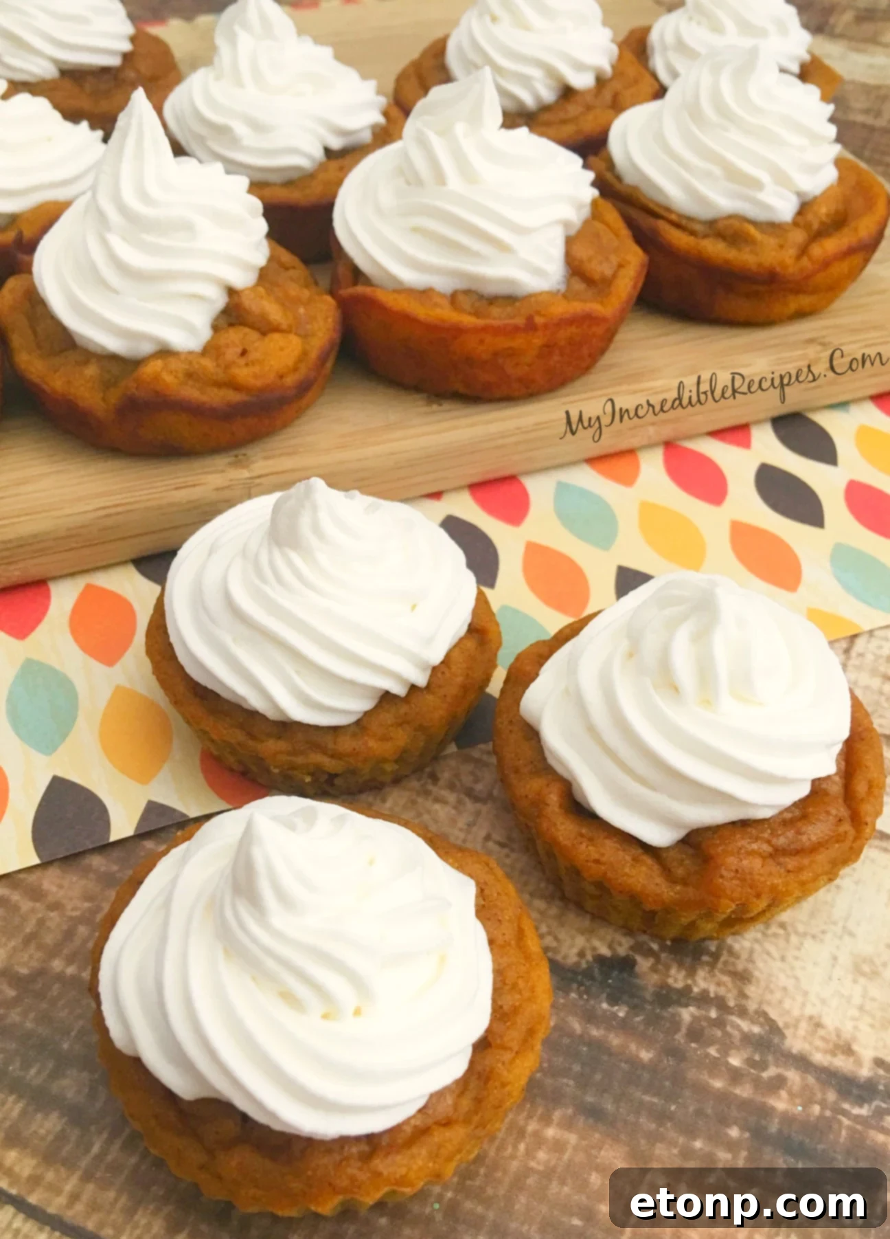 Three pumpkin pie cupcakes, each topped with a generous swirl of whipped cream.