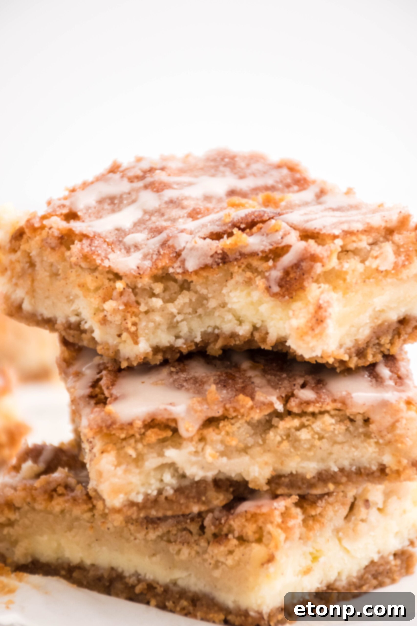 Front view of three Snickerdoodle Cheesecake Bars stacked with a bite removed from the top bar.