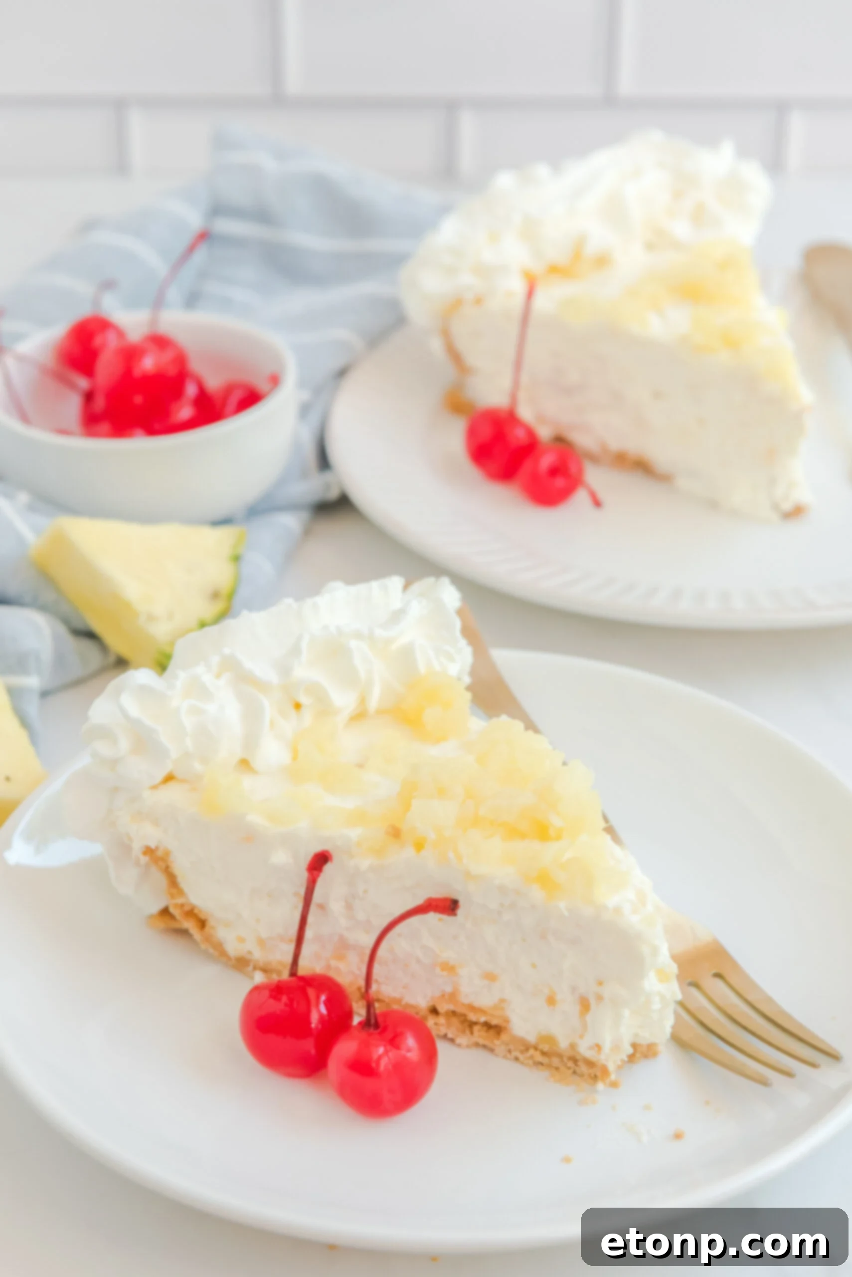 Chilled Pineapple Cheesecake Bliss 2 No Bake Pineapple Cheesecake Pie on a white plate with maraschino cherries next to a slice