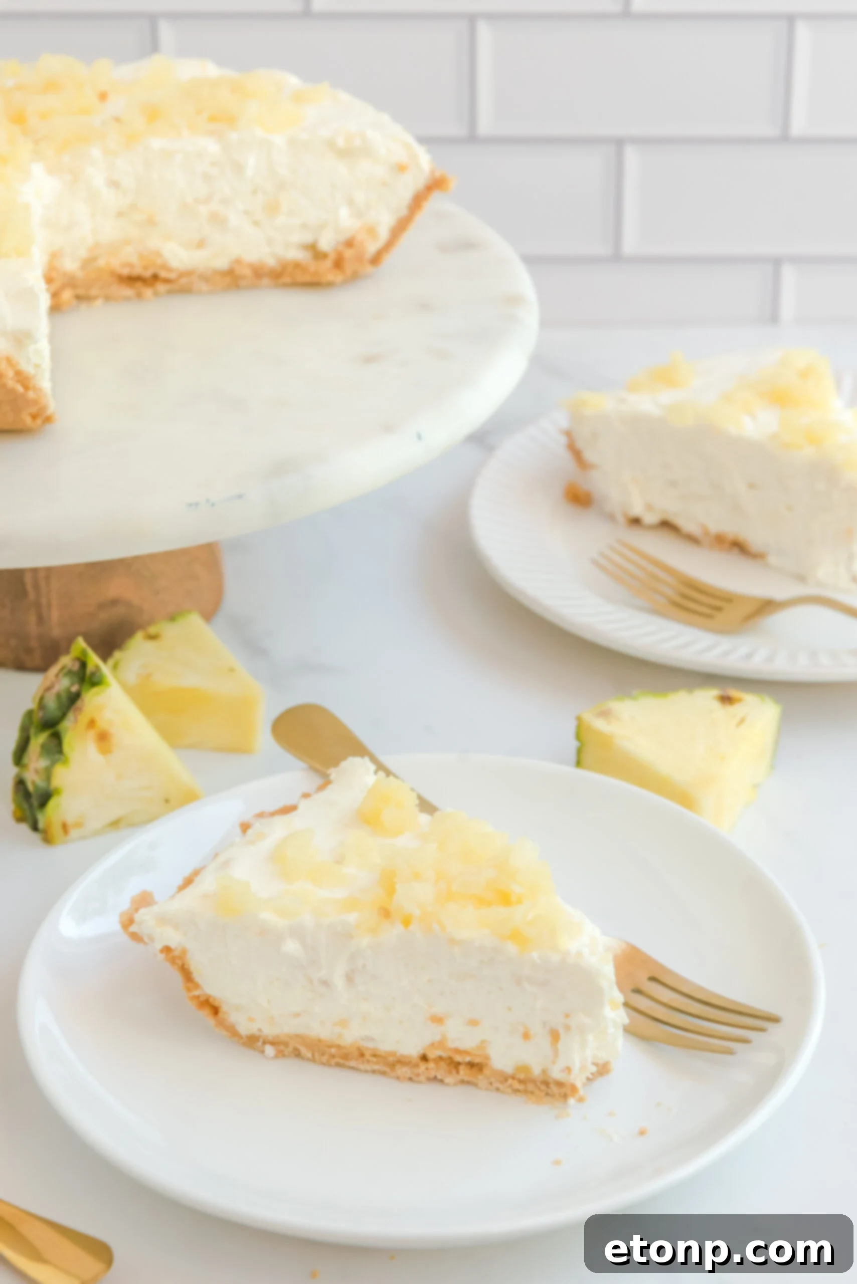 Chilled Pineapple Cheesecake Bliss 15 Front view of a slice of No Bake Pineapple Cheesecake on a white plate served with a gold fork.