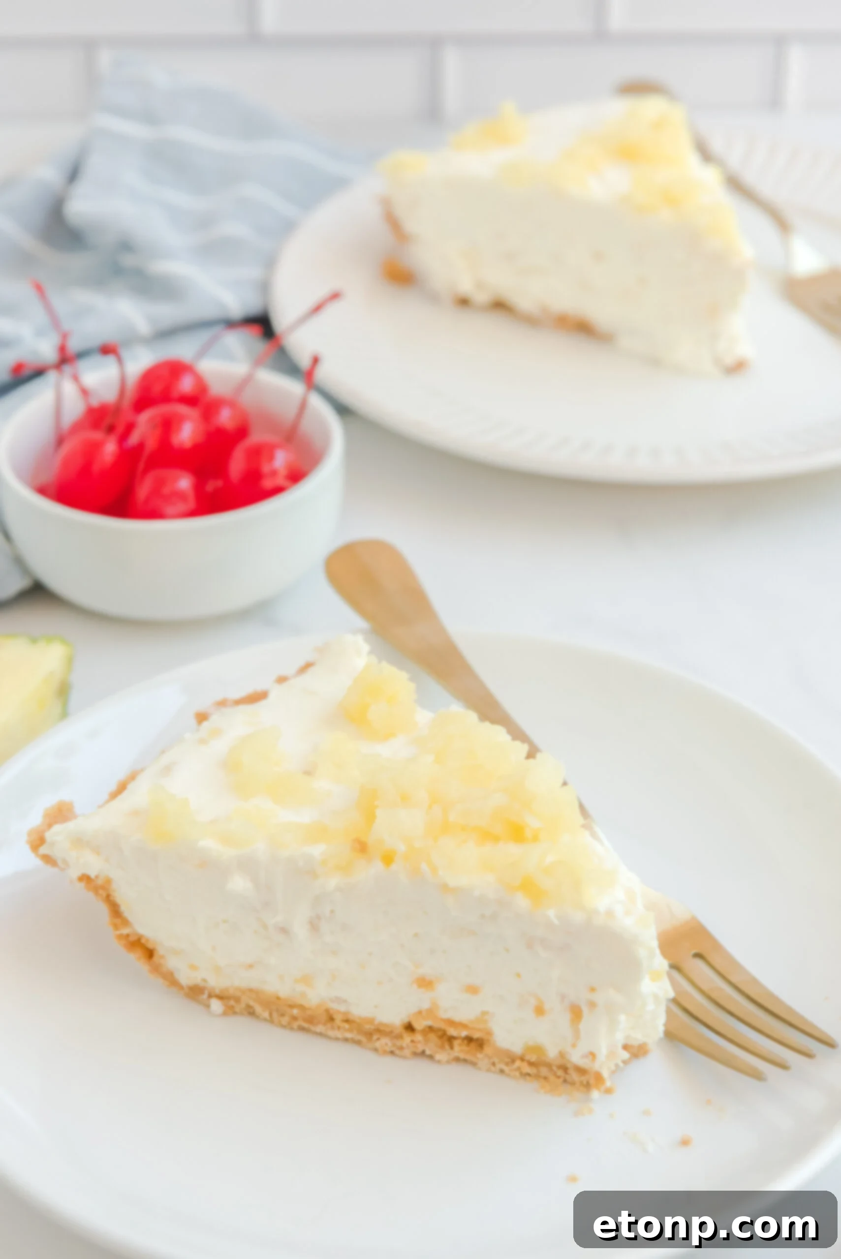 Chilled Pineapple Cheesecake Bliss 17 Side view of a slice of No Bake Pineapple Cheesecake served on a white plate with a gold fork.