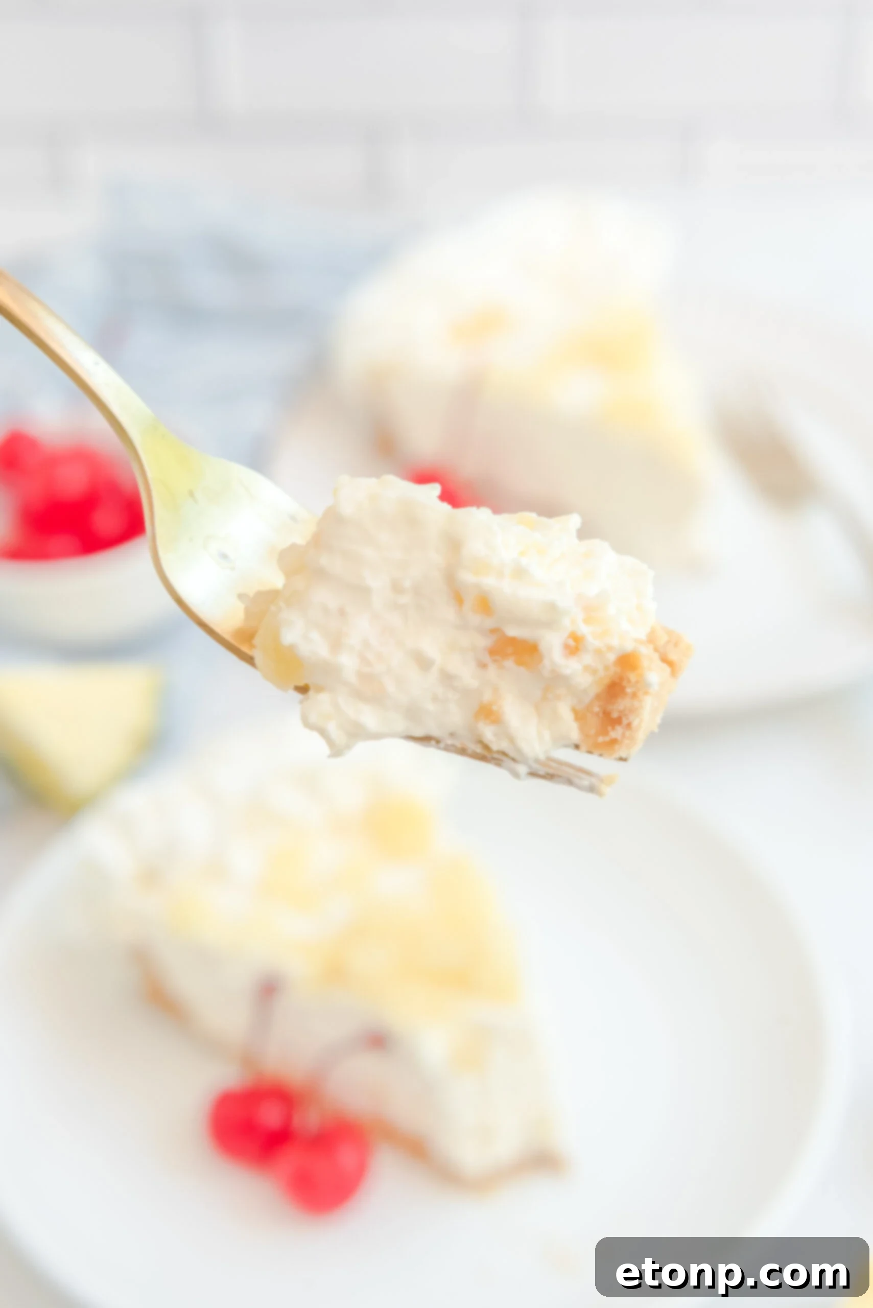 Chilled Pineapple Cheesecake Bliss 20 Up close view of a bite of No Bake Pineapple Cheesecake on a gold fork.