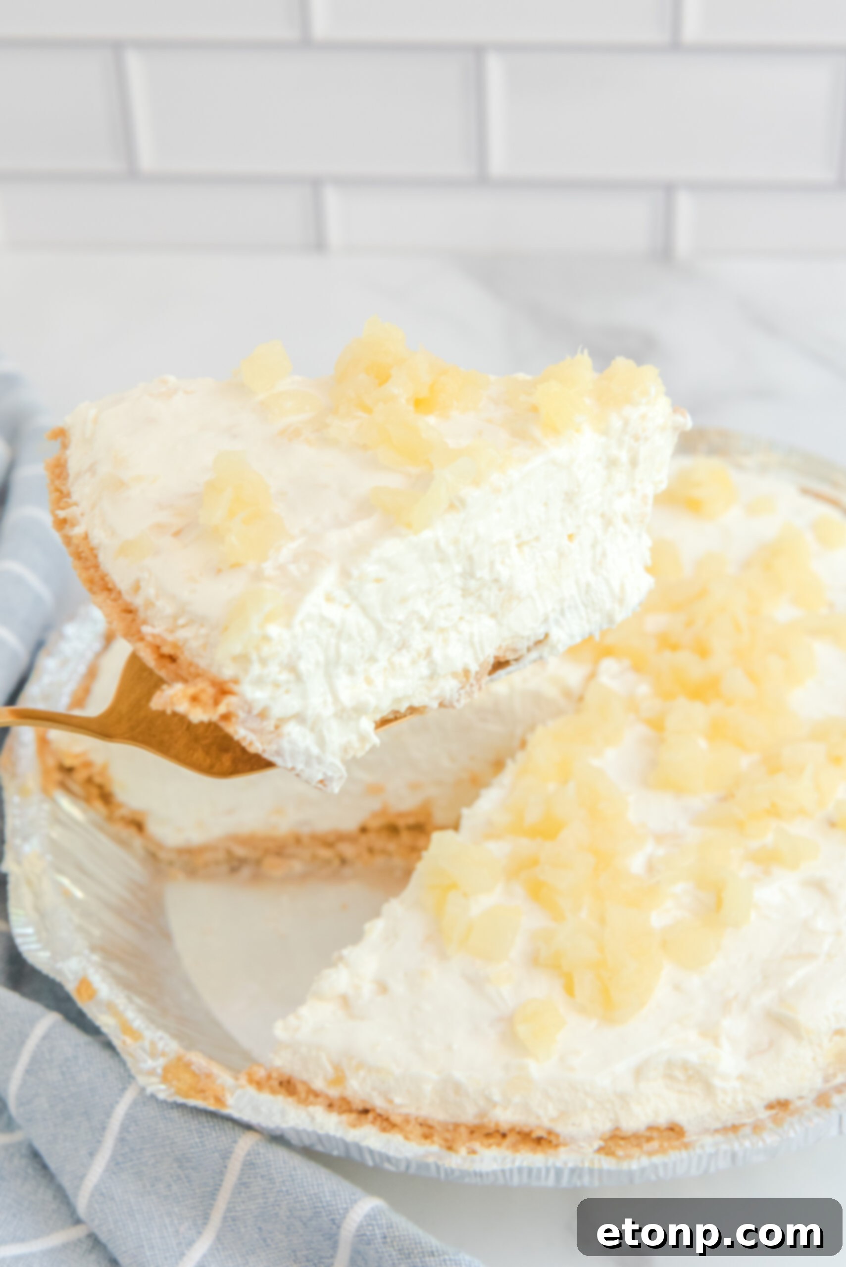 Chilled Pineapple Cheesecake Bliss 6 Side view of a slice of No Bake Pineapple Cheesecake on a gold cake server.