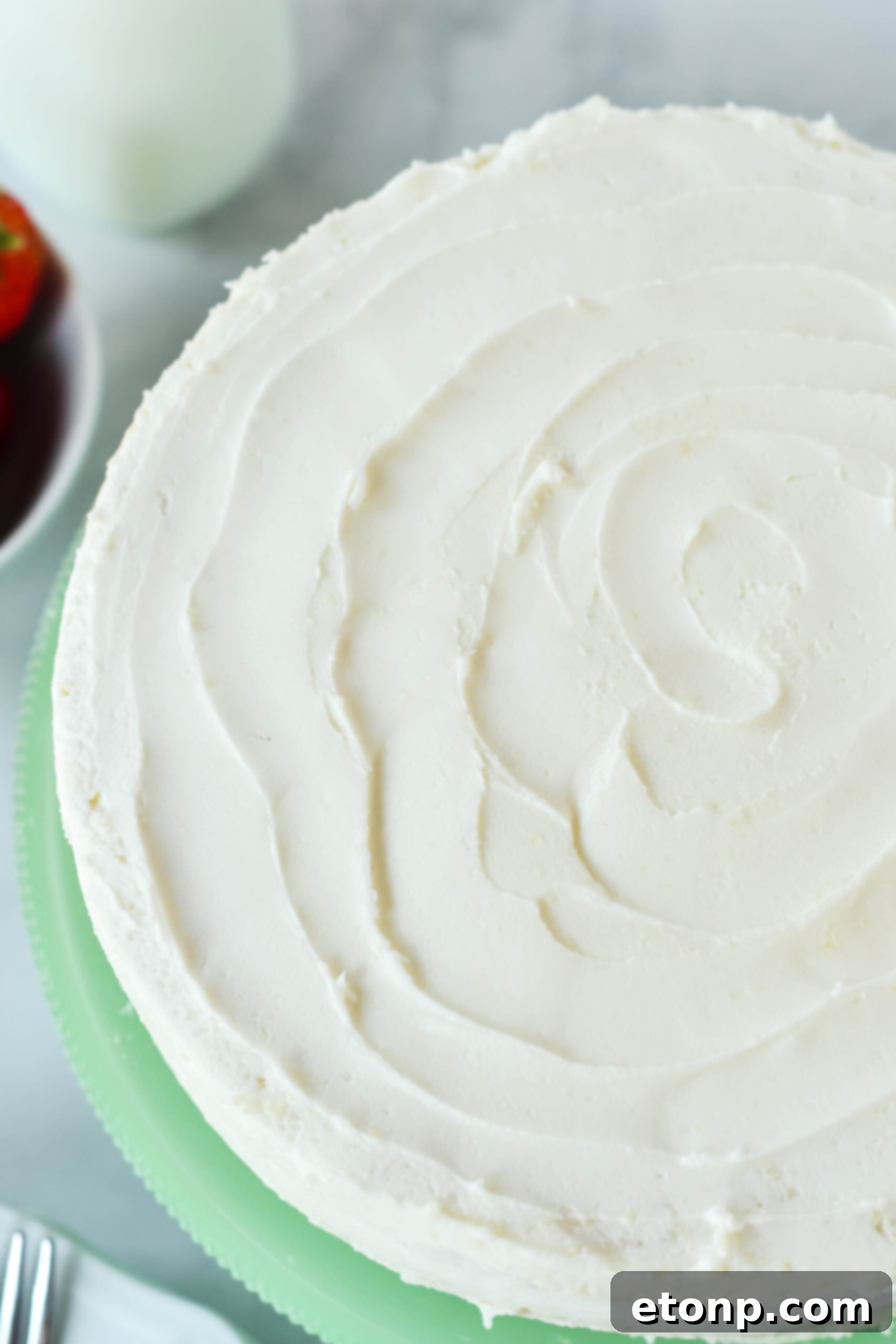 Overhead view of a beautifully frosted Classic Vanilla Cake on an elegant green cake stand.