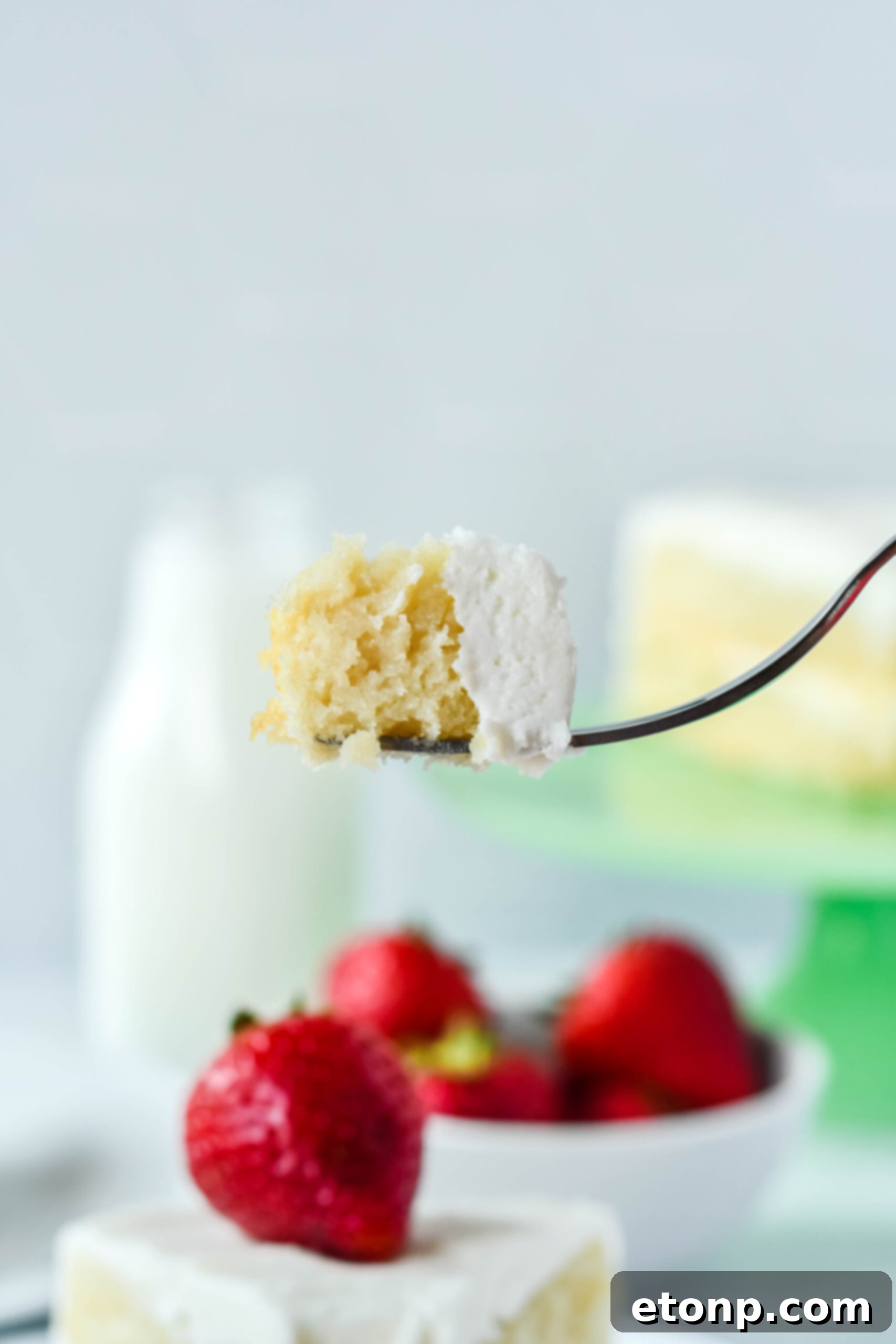 Side view of a perfect bite of Classic Vanilla Cake on a silver fork, showcasing its soft crumb.