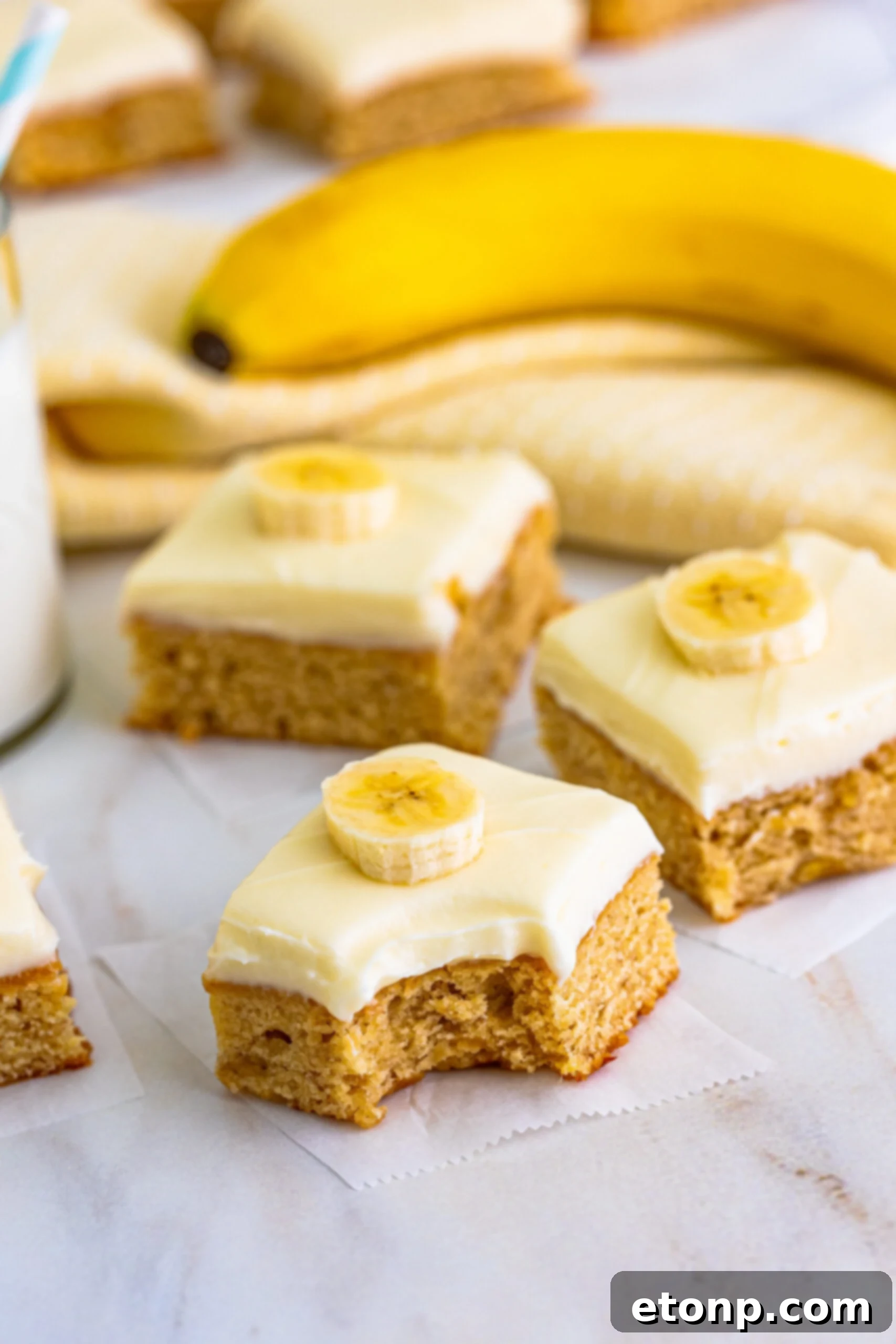 Ultimate Banana Brownies 7 Front view of Banana Brownies on parchment paper, with one piece missing a bite.