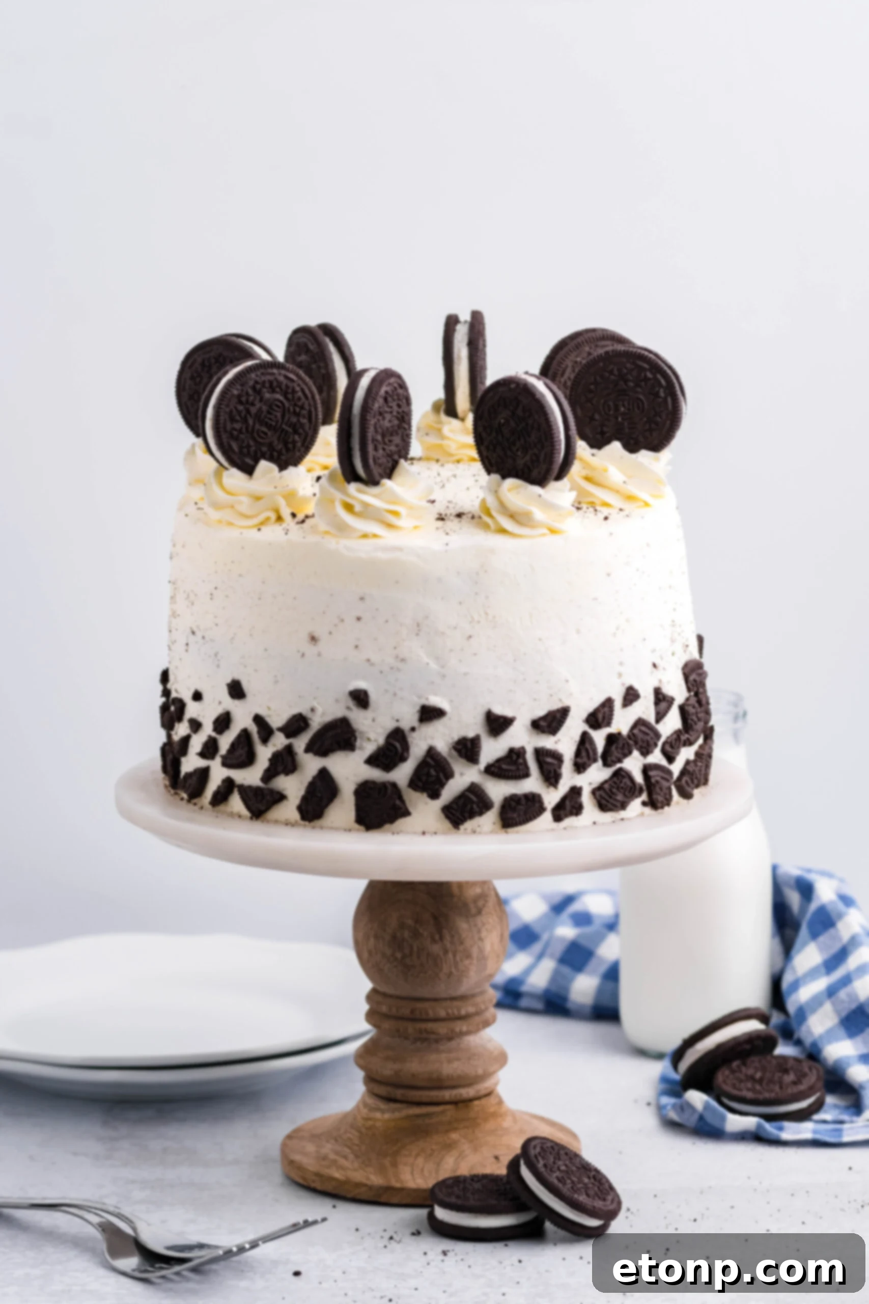 Front view of Double Stuffed Oreo Cake on a white and wooden cake stand.