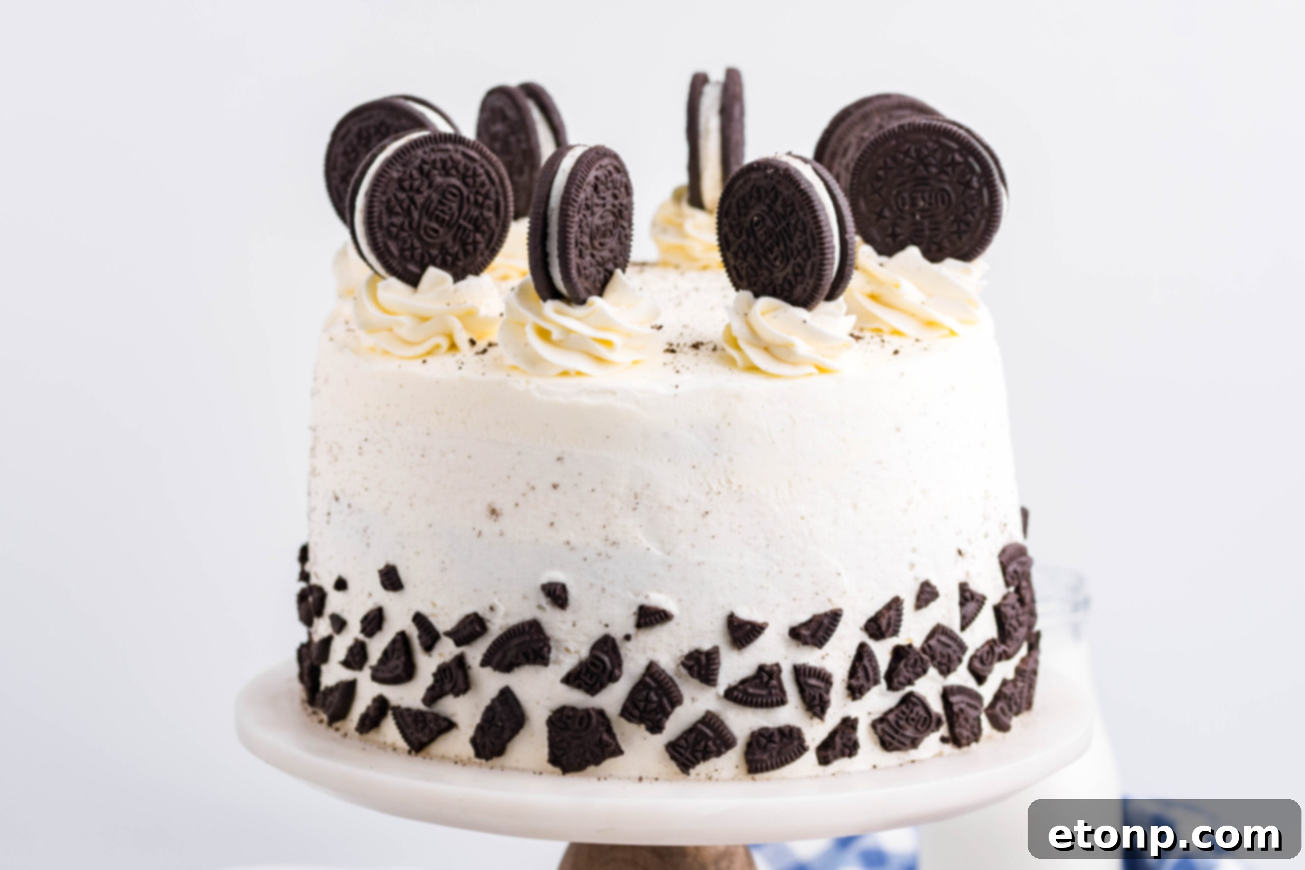 Front view of Double Stuffed Oreo Cake on a white and wood cake stand.