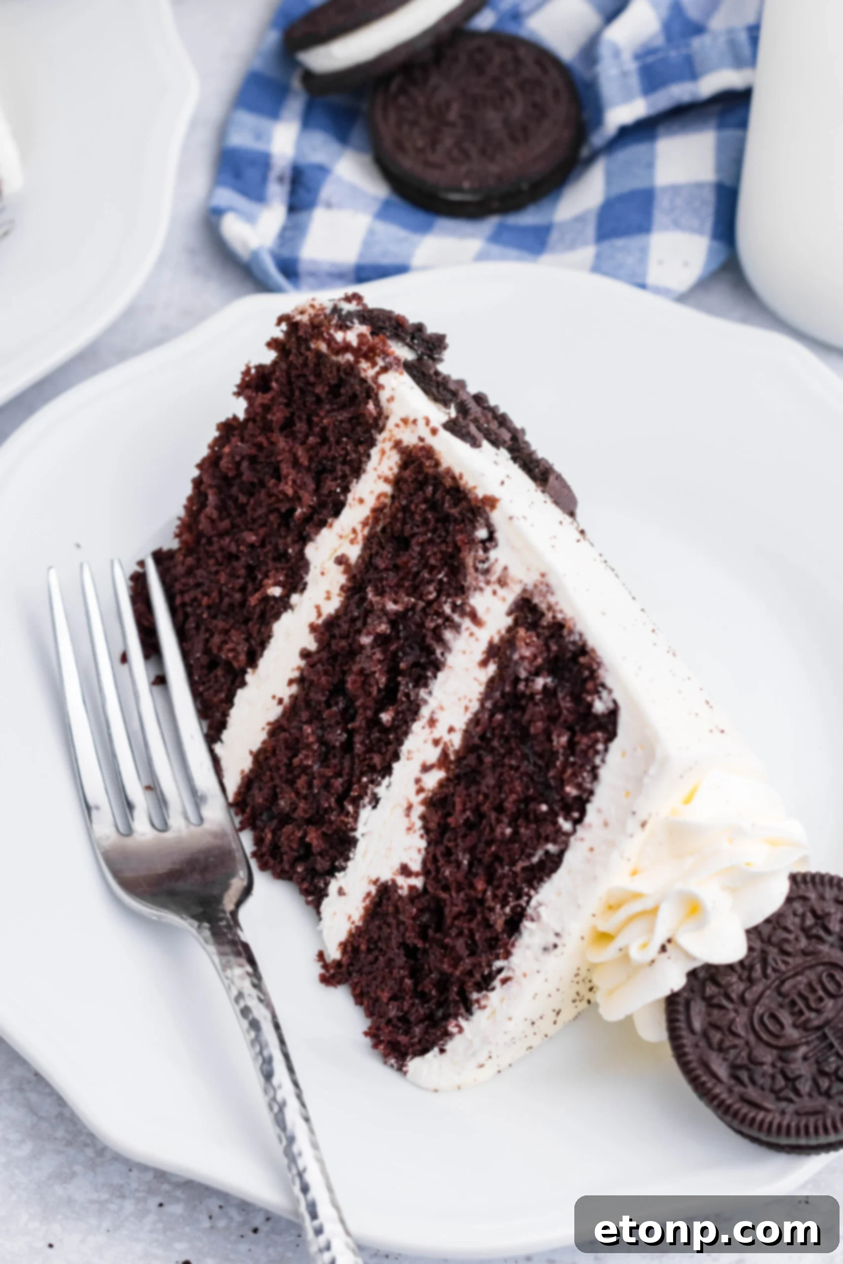 Overhead view of a slice of Double Stuffed Oreo Cake served on a white plate with a silver fork.