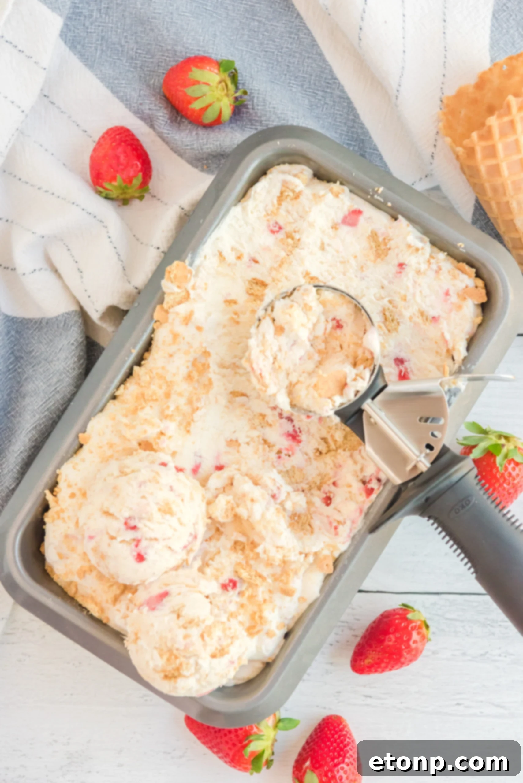 overhead shot view of an ice cream scoop scooping Strawberry Cheesecake Ice Cream.