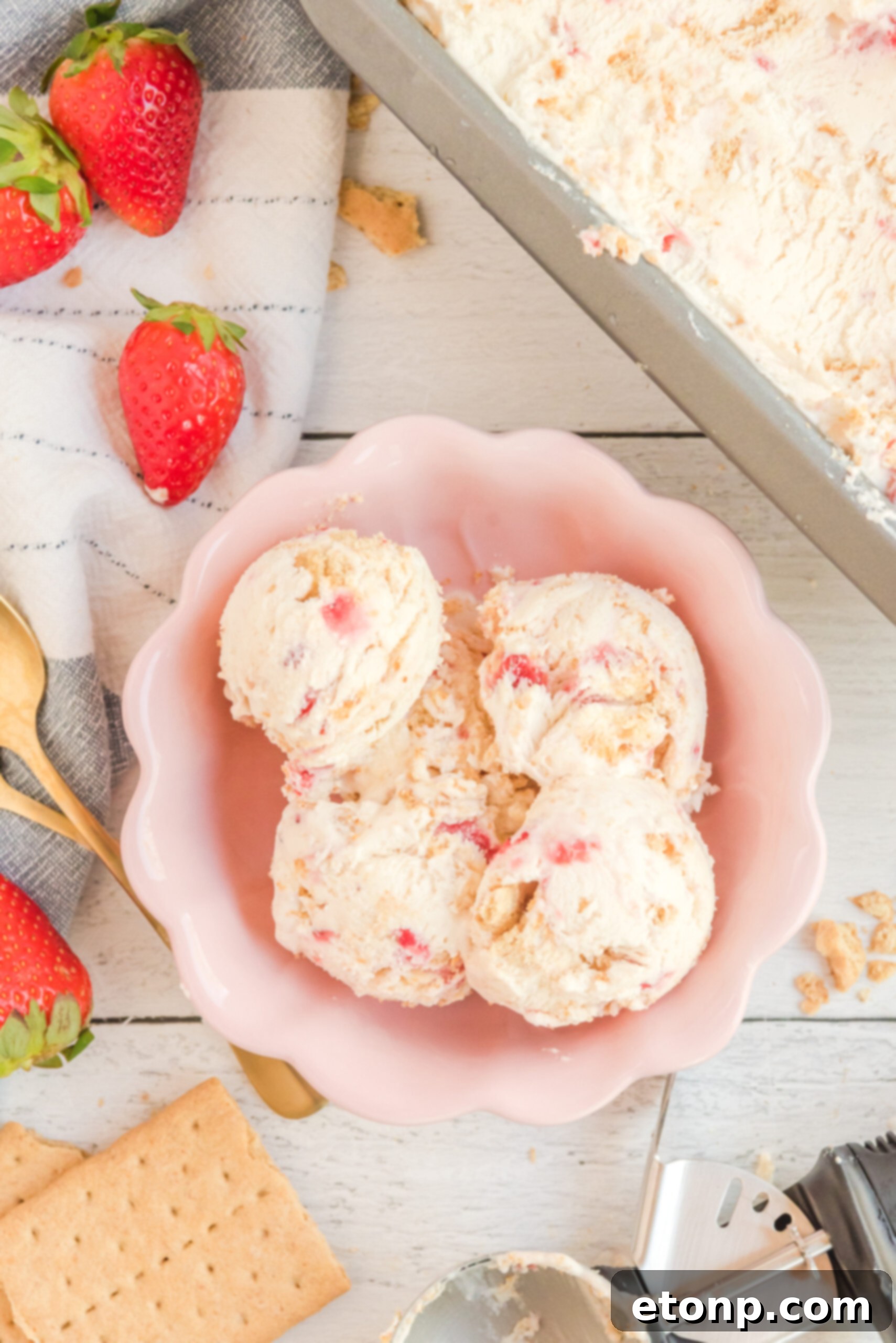 Overhead view of scoops of Strawberry Cheesecake Ice Cream in a pink bowl.