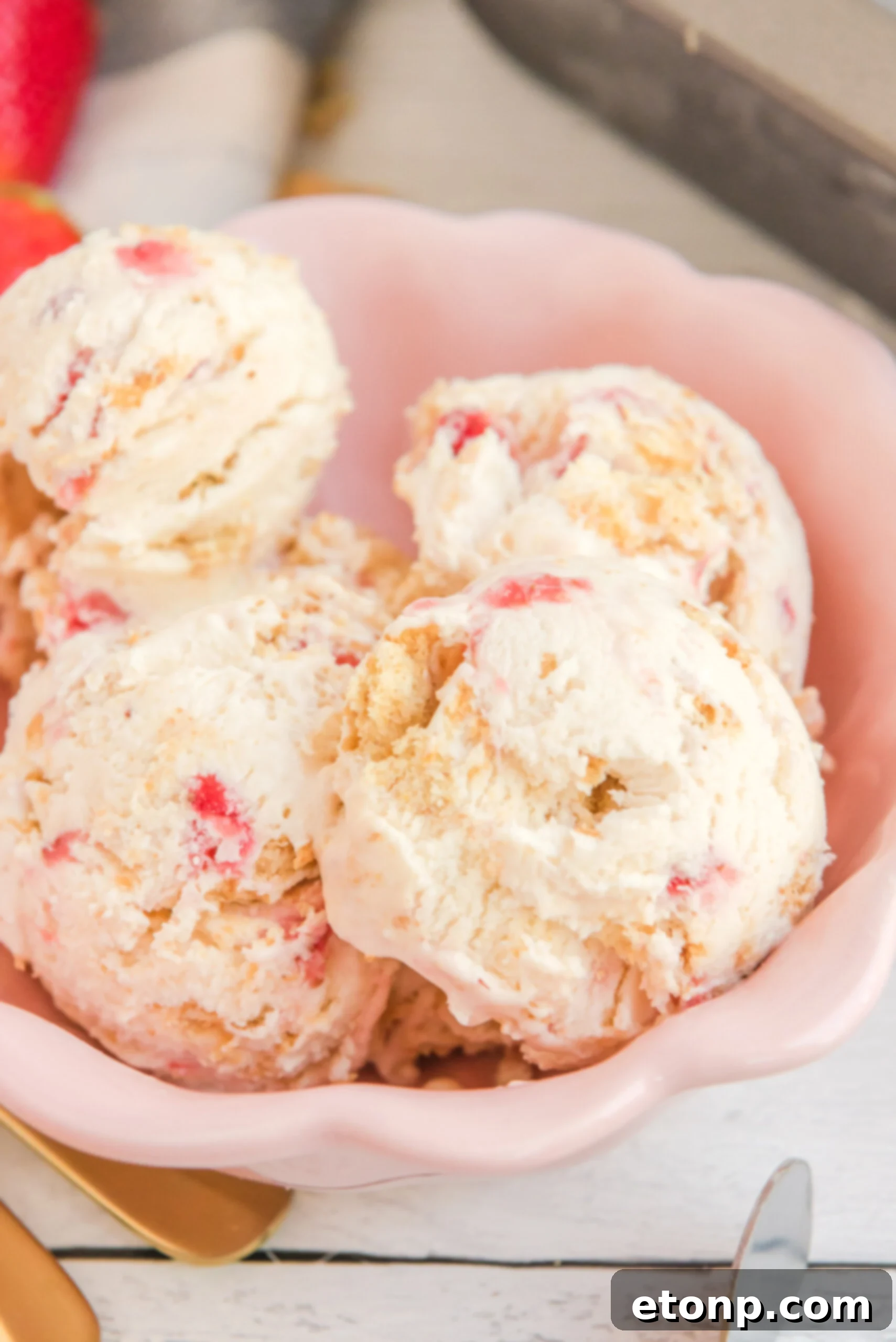 Close up view of scoops of Strawberry Cheesecake Ice Cream in a pink bowl.