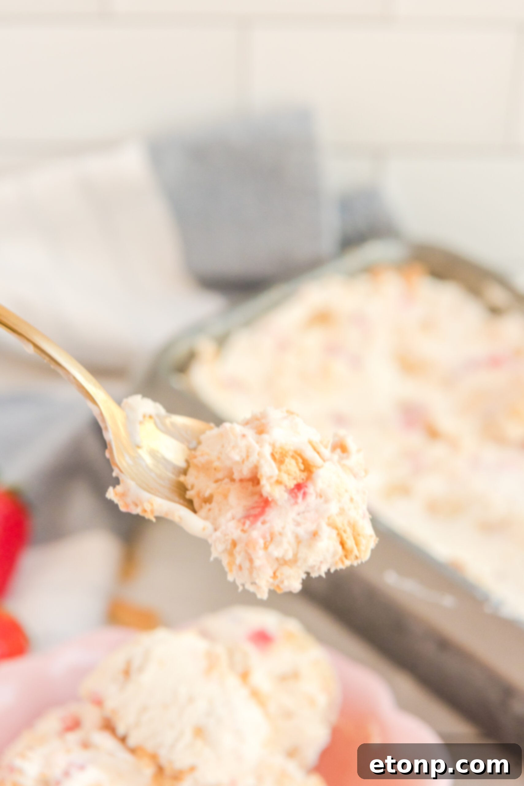 Front view of a bite of Strawberry Cheesecake Ice Cream on a gold spoon.