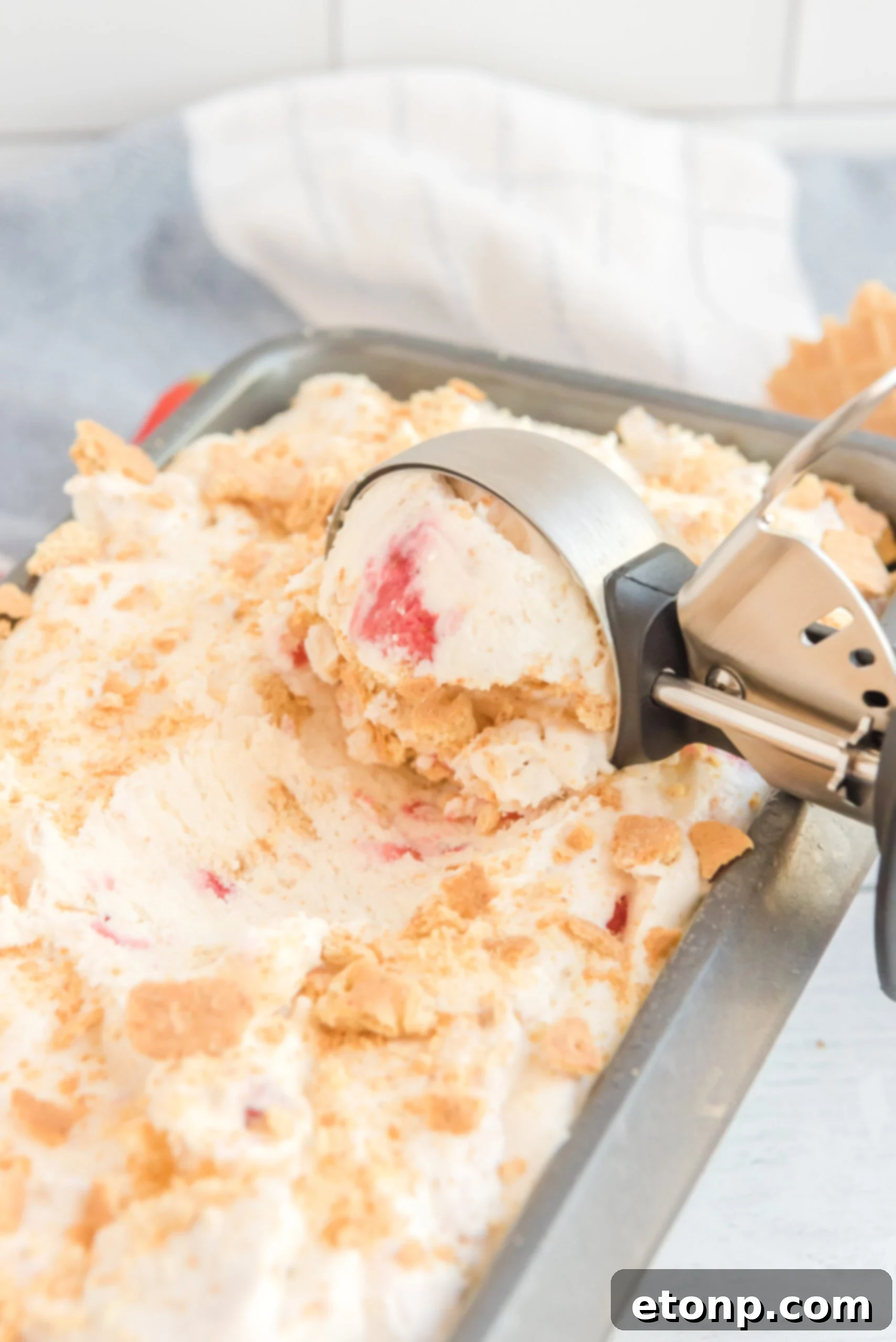 Close up view of an ice cream scoop scooping Strawberry Cheesecake Ice Cream.